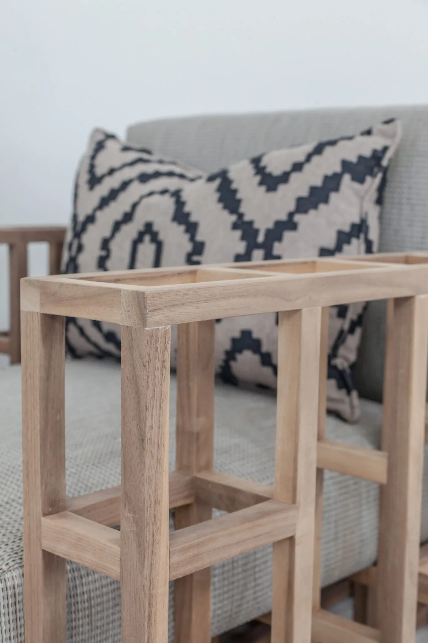 Multifamily interior detail: slatted wood armchair arm before a geometric print pillow