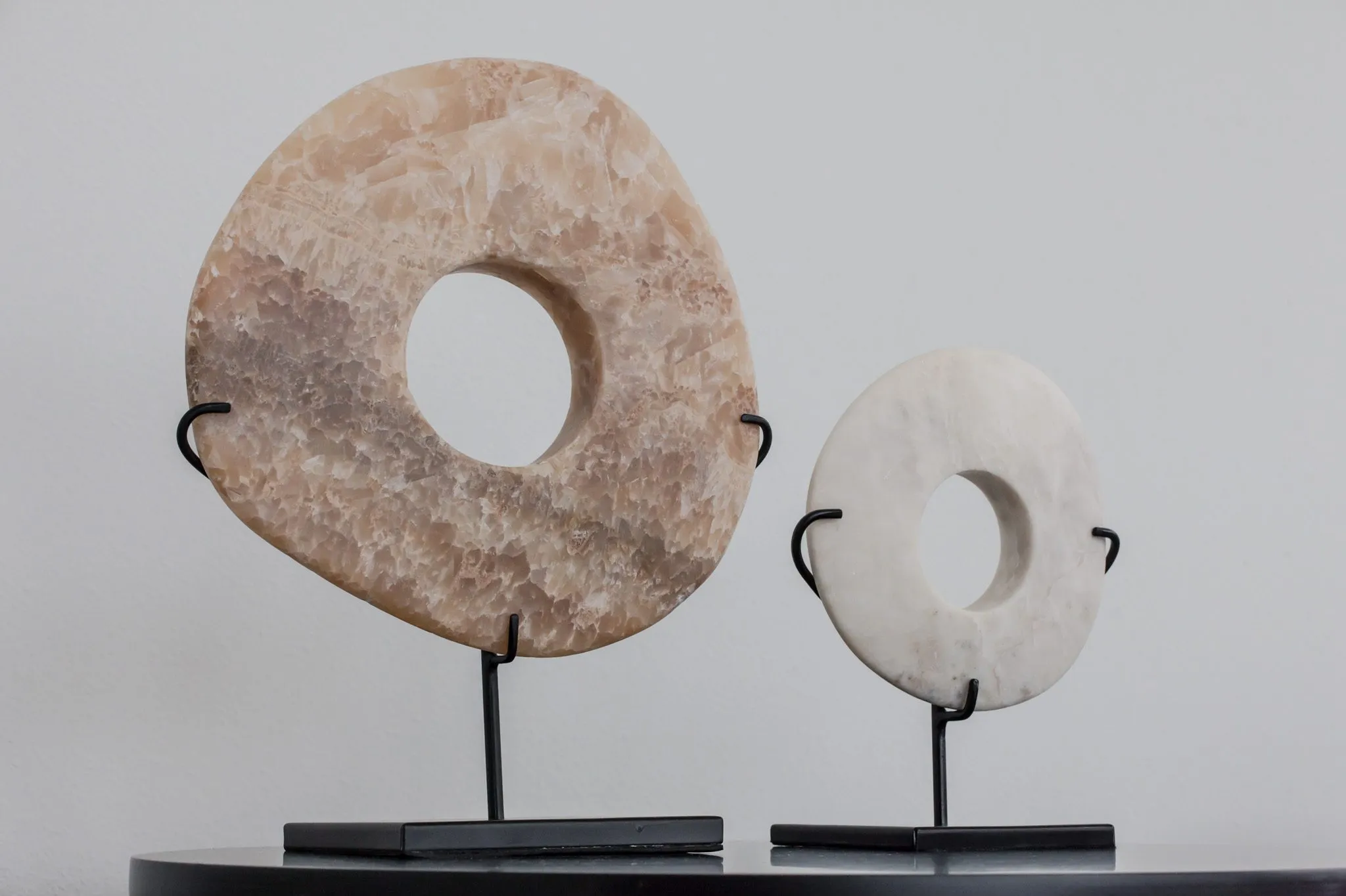 Multifamily interior detail: two stone ring sculptures on black stands, one tan and one white