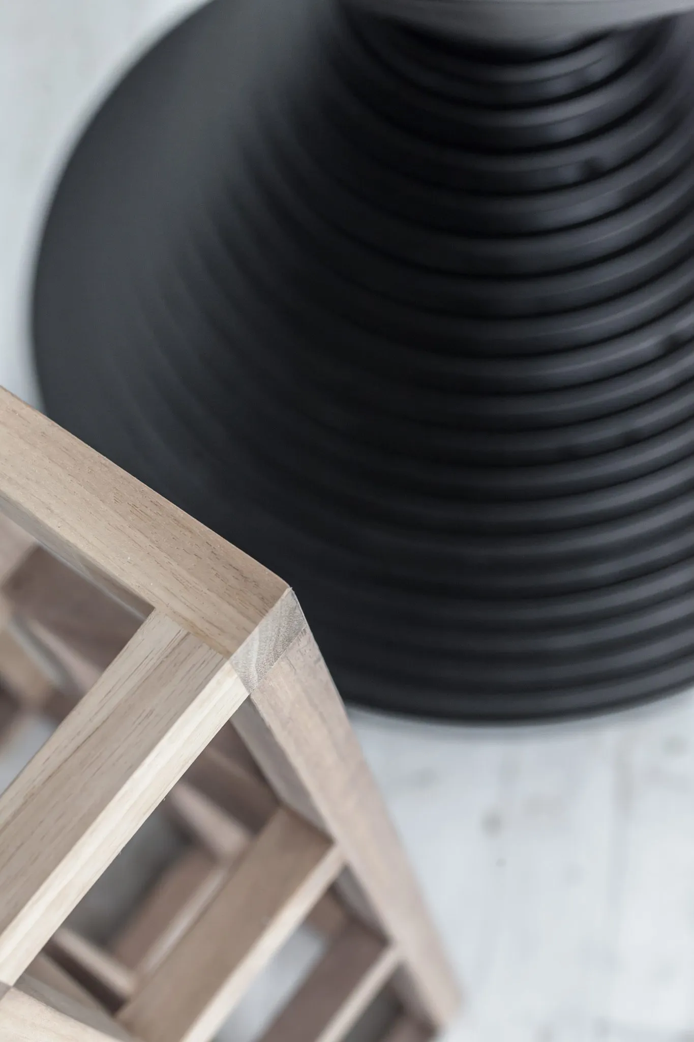 Multifamily interior detail: overhead view of a slatted wood armchair corner beside the black ribbed hourglass table