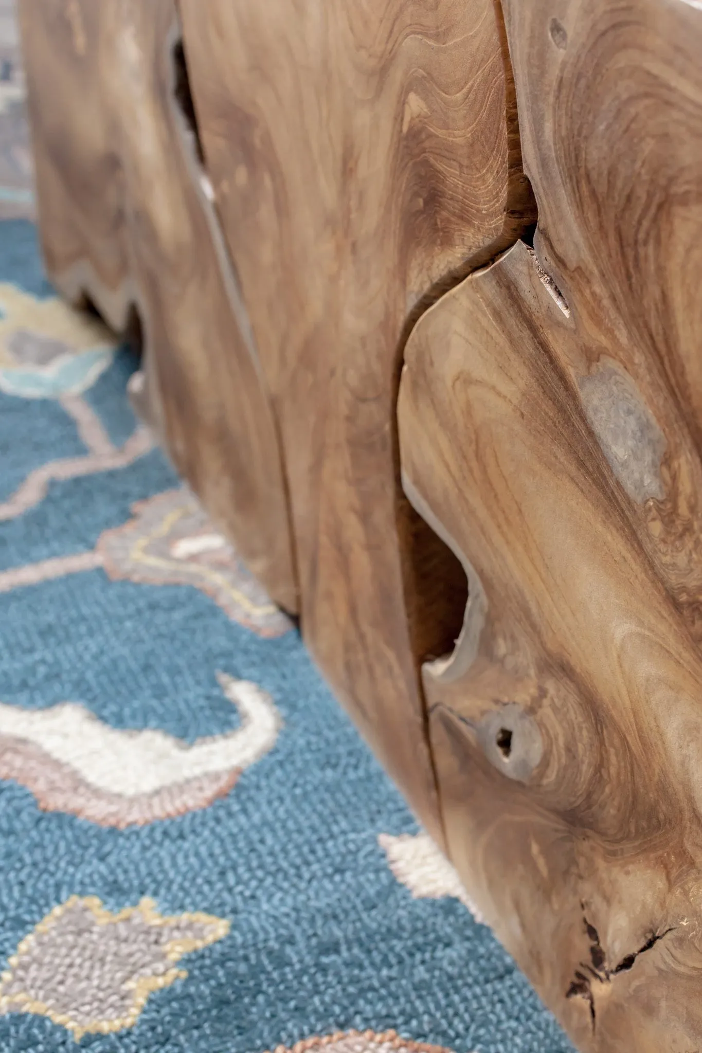 Multifamily interior detail: solid timber block coffee table on a blue patterned rug