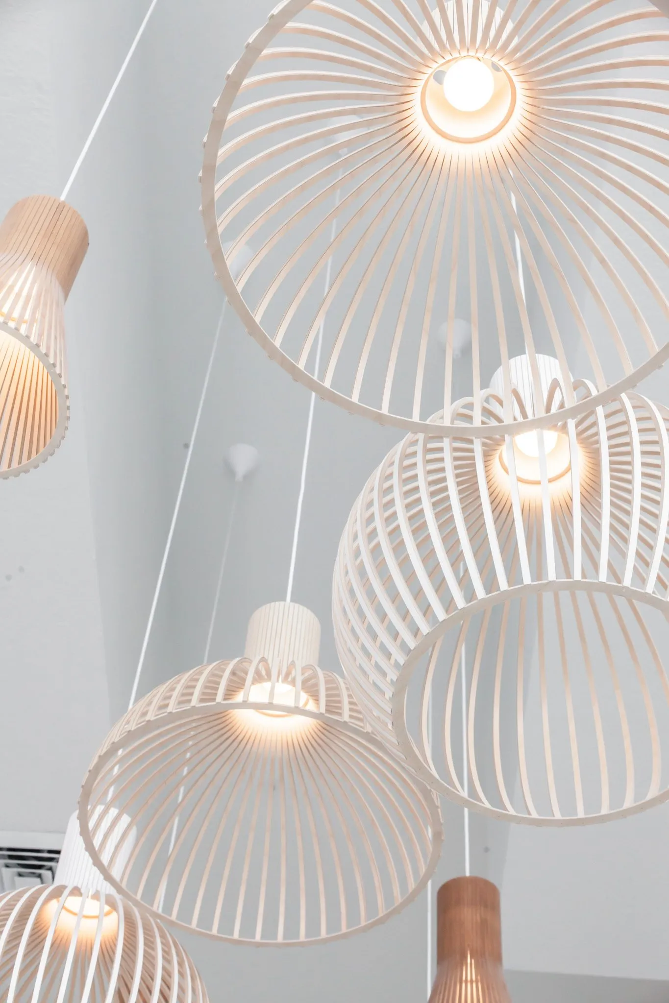 Multifamily interior detail: looking up into pale wood ribbon pendants hung at staggered heights