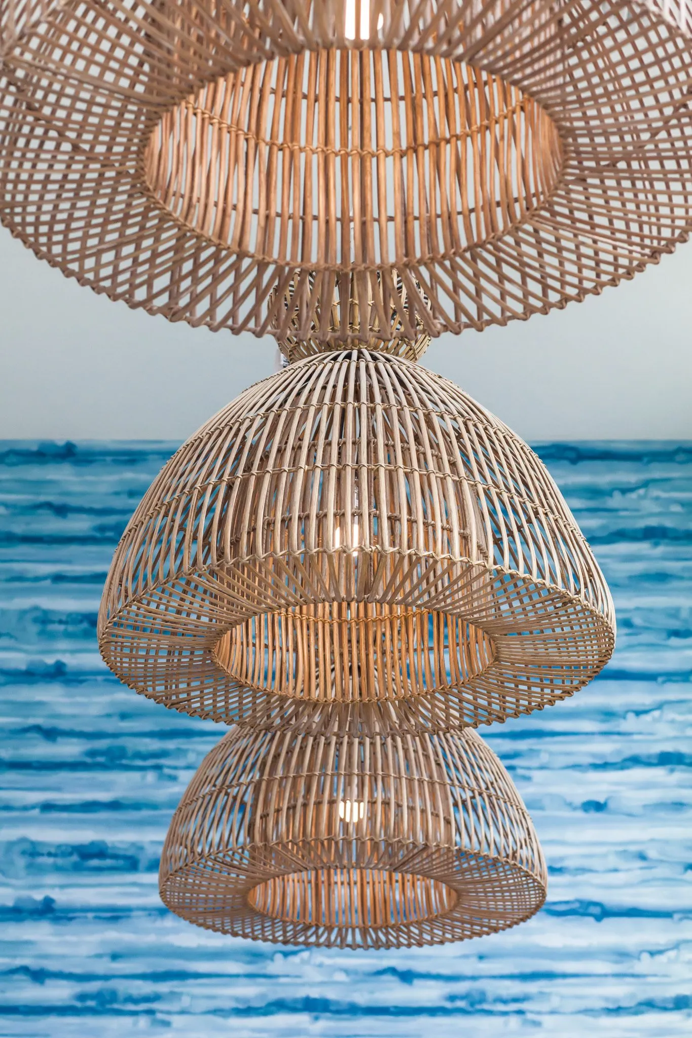 Multifamily interior detail: three nested rattan pendants against the blue water pattern wall