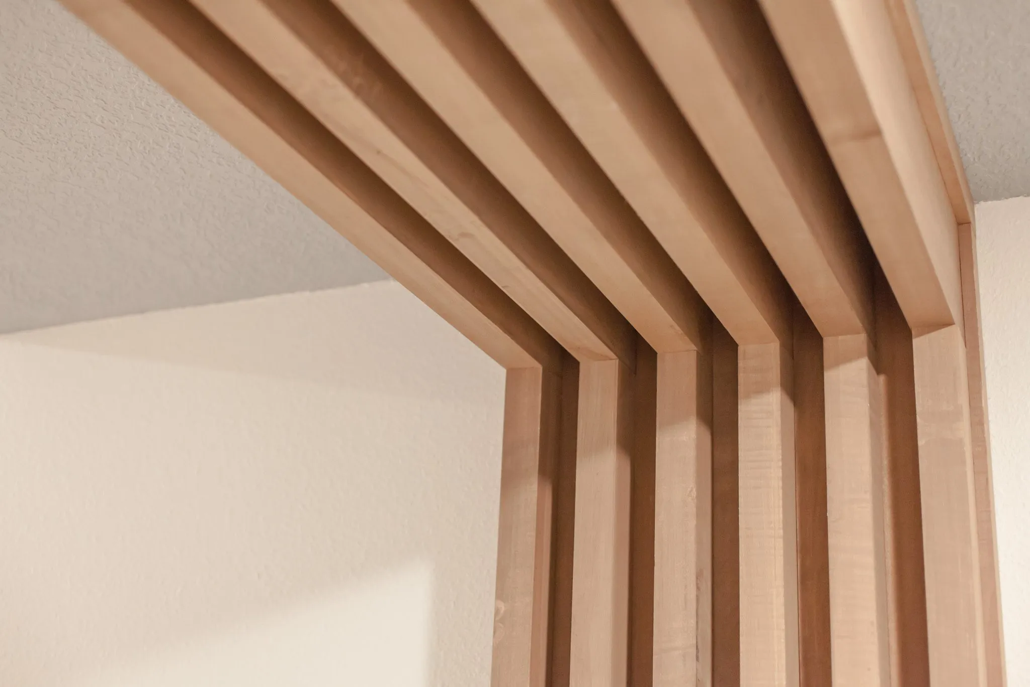 Multifamily interior detail: wood slats wrapping from ceiling to wall at a corridor portal