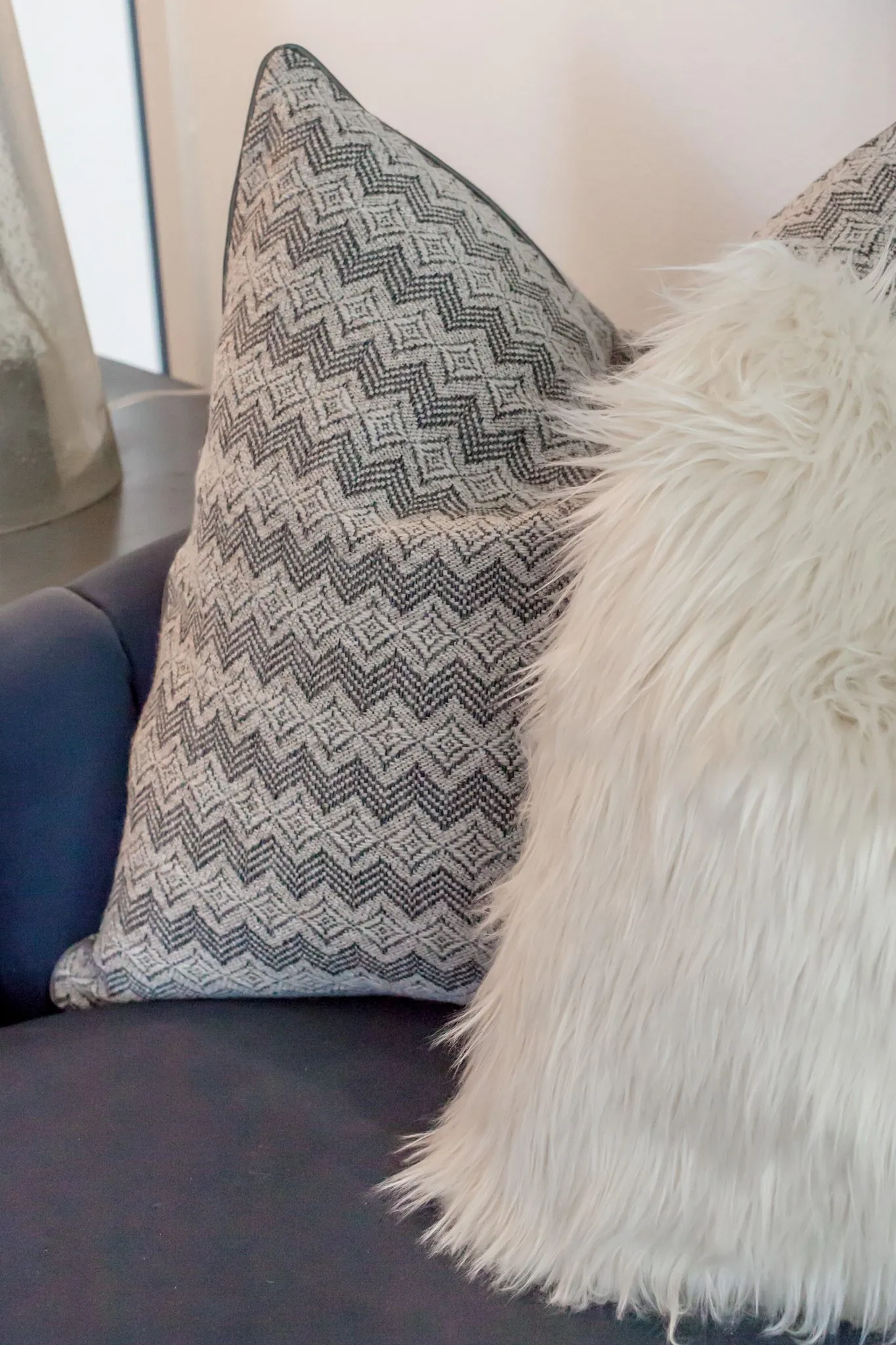 Multifamily interior detail: grey zigzag pillow and sheepskin pillow on a charcoal sofa
