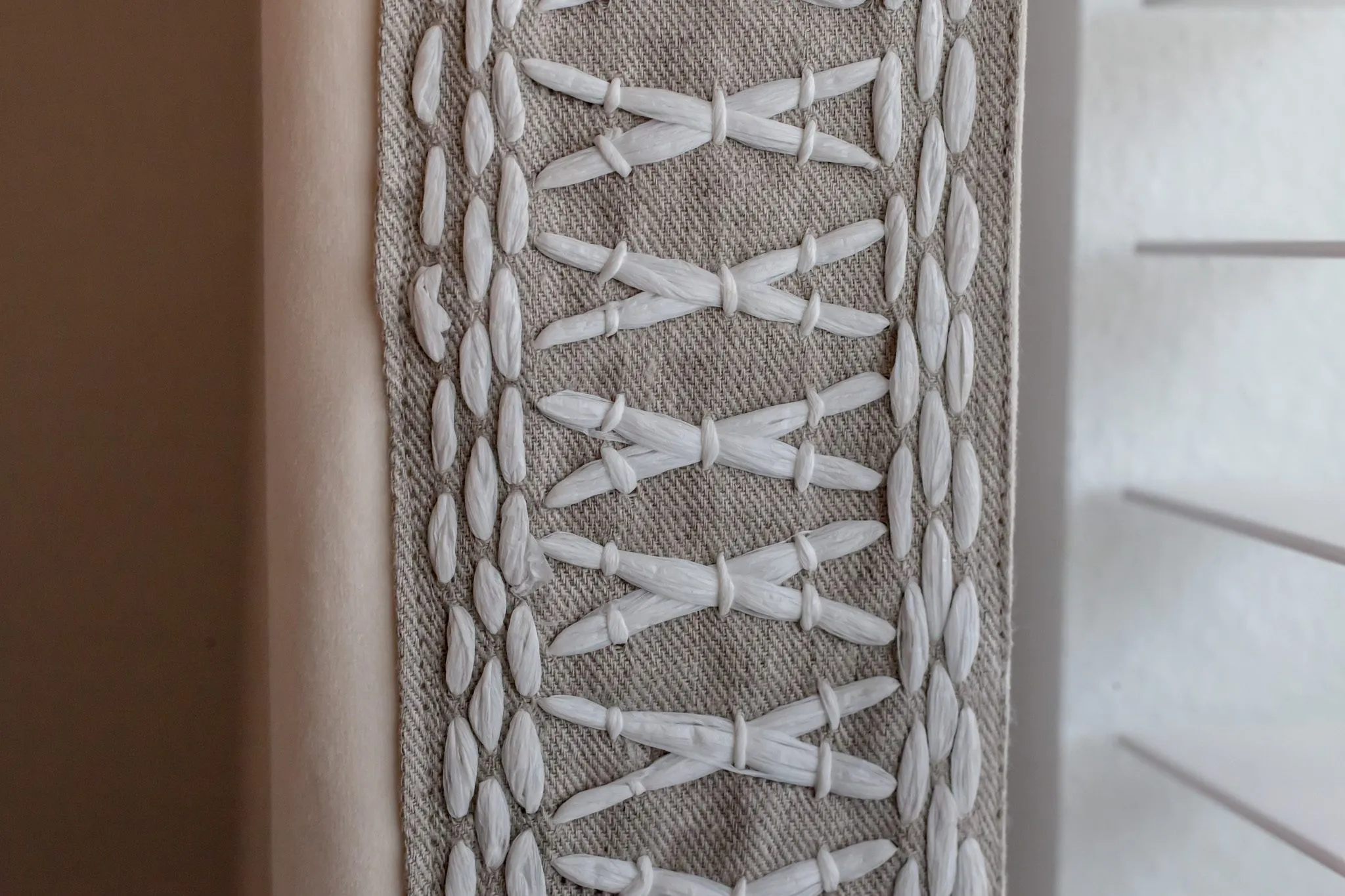 Multifamily interior detail: linen curtain border embroidered with white crossed stitching