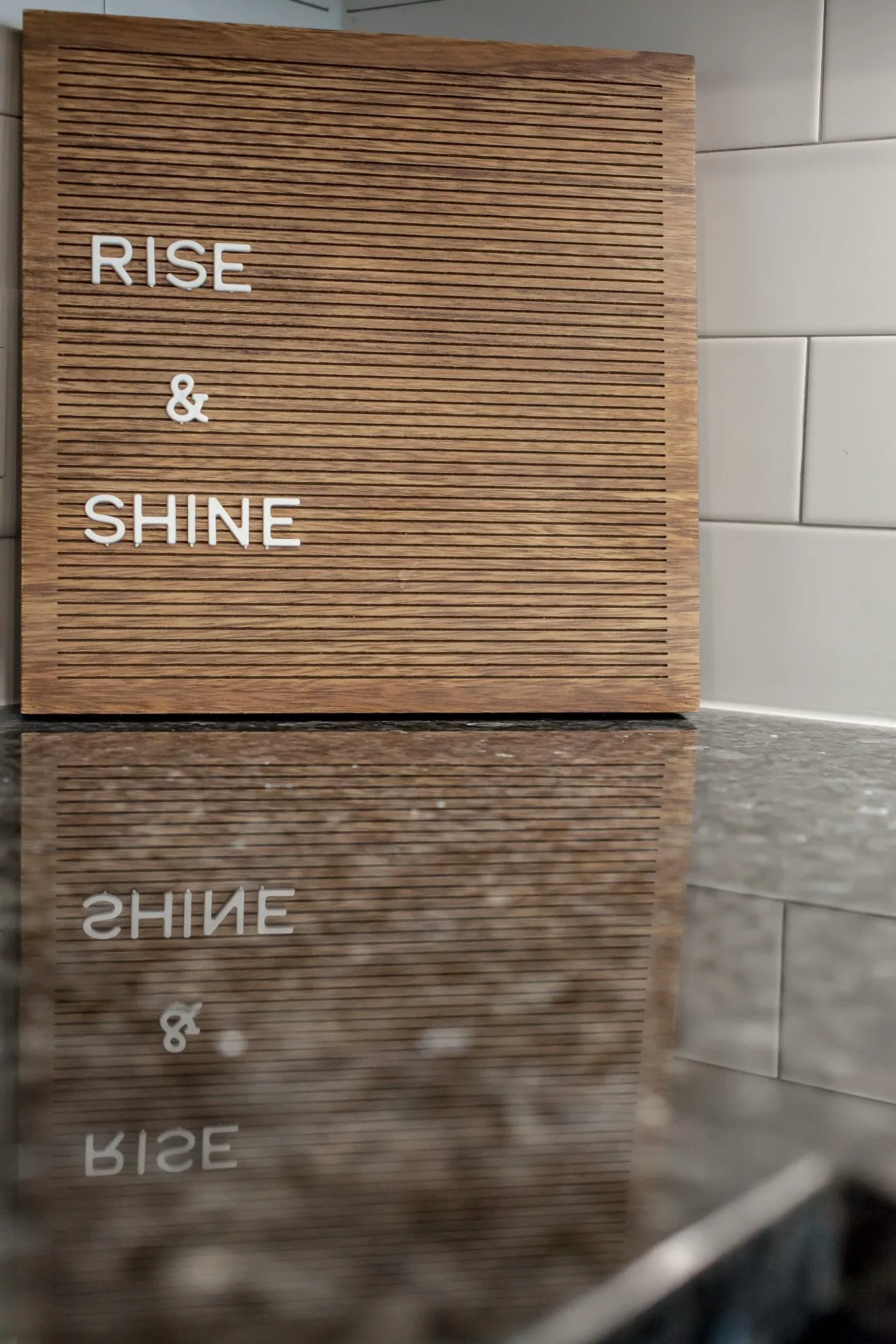 Multifamily interior detail: wood letter board reading Rise & Shine reflected in a granite counter