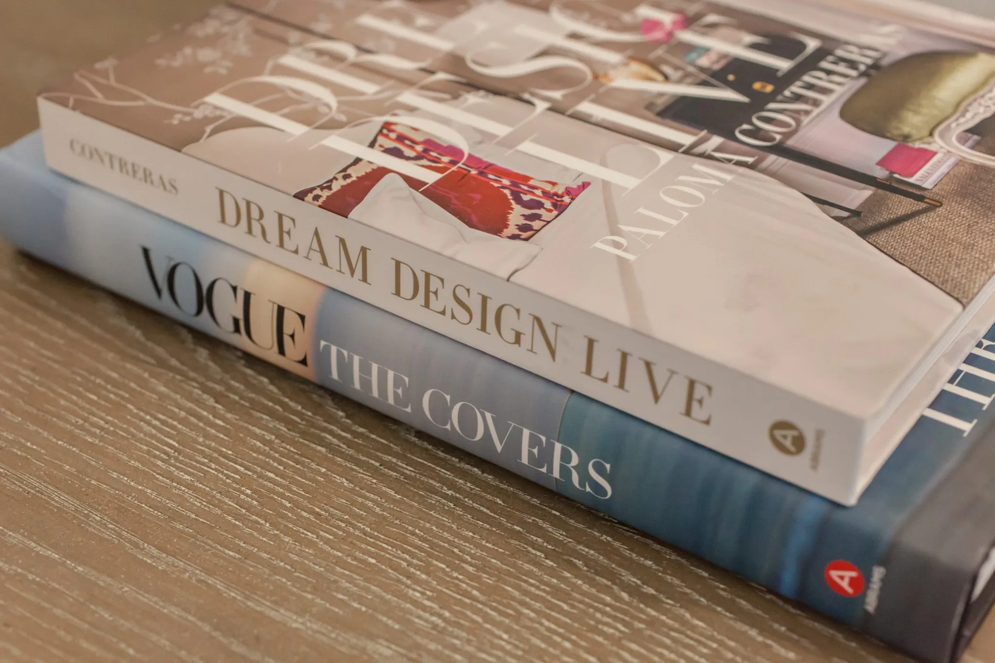 Multifamily interior detail: two stacked coffee table books on a grey wood surface