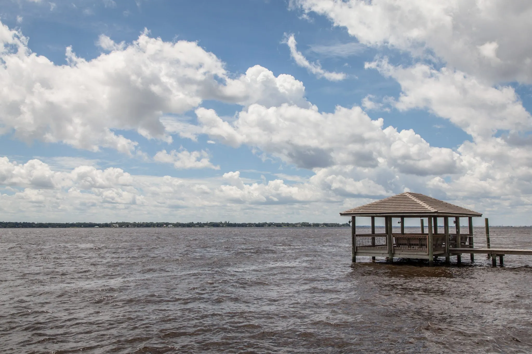 Multifamily community exterior: covered boat dock on the river under a cloudy sky