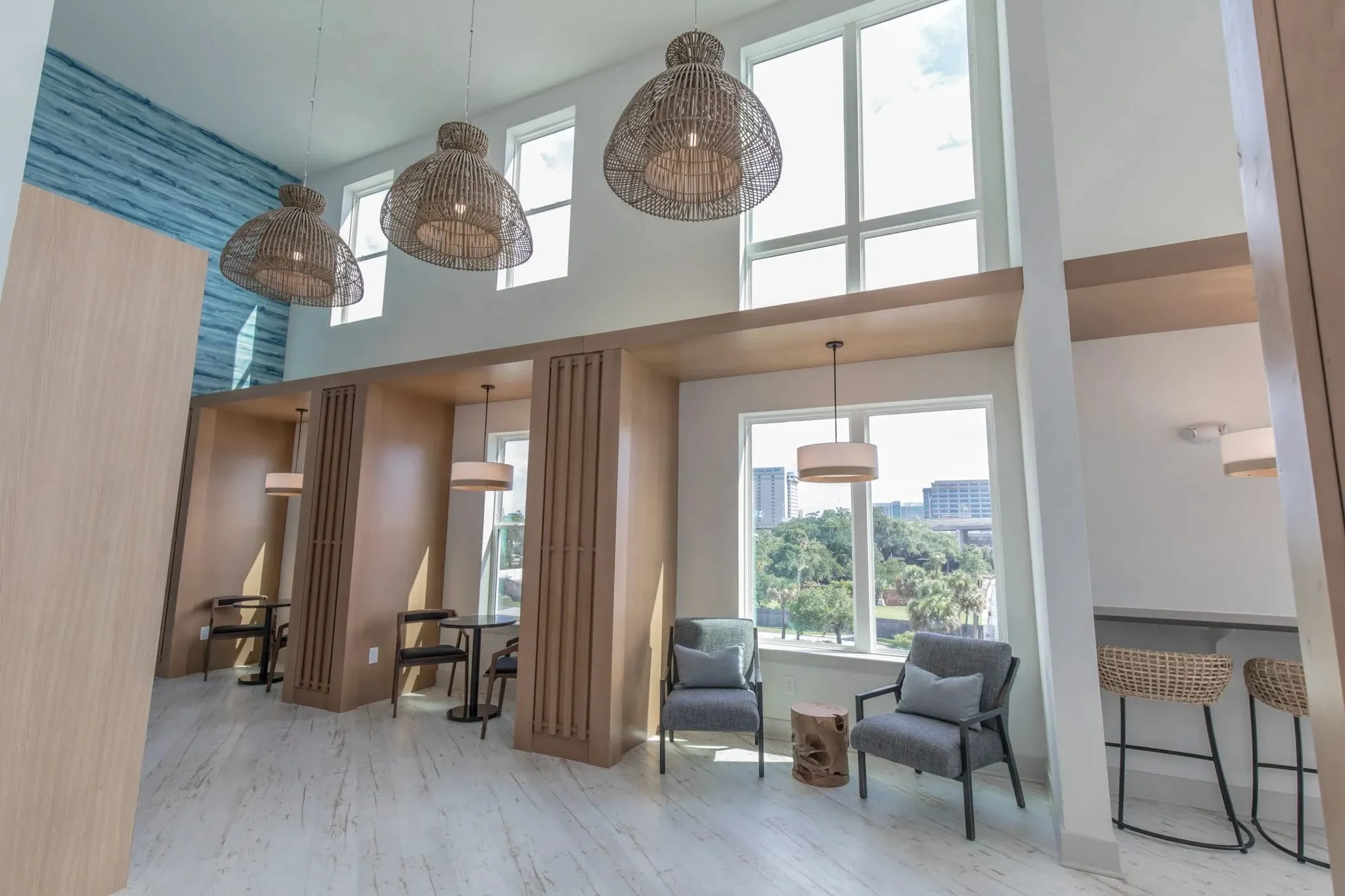 Multifamily amenity coworking area with woven pendants above the window bar and lounge chairs in the double-height room