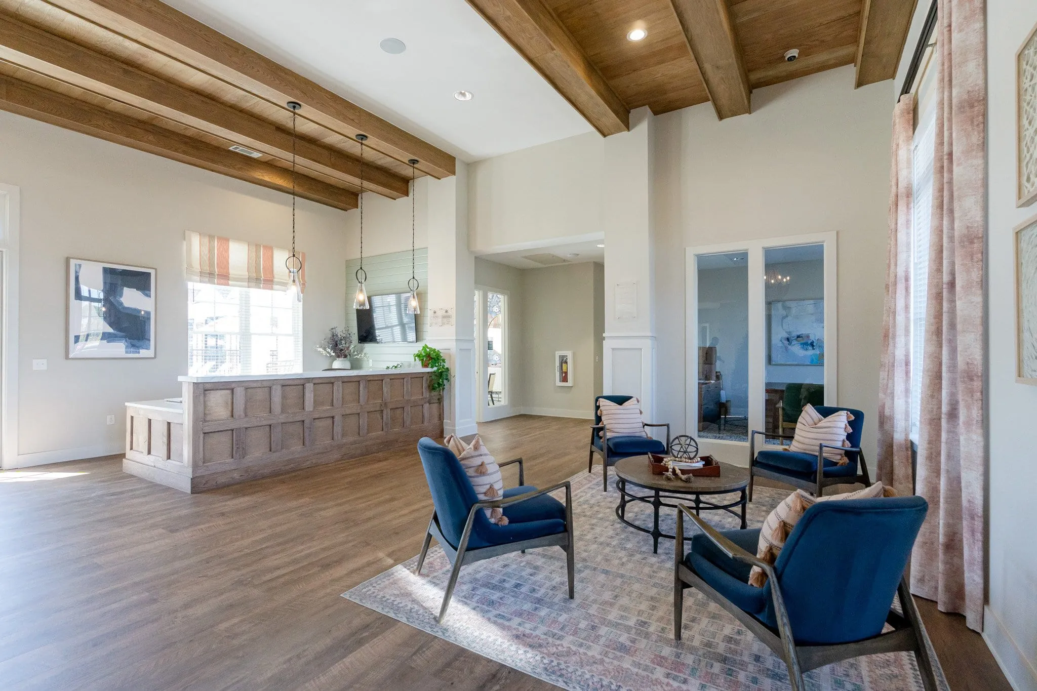 Multifamily amenity leasing center with wood beams above blue lounge chairs, interior design by Banko Design at South & Twenty, Cartersville, Georgia