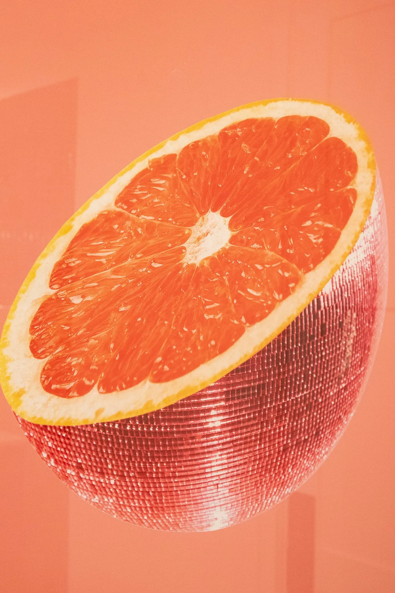 Multifamily interior detail: framed artwork of a grapefruit slice rendered as a disco ball on a coral ground