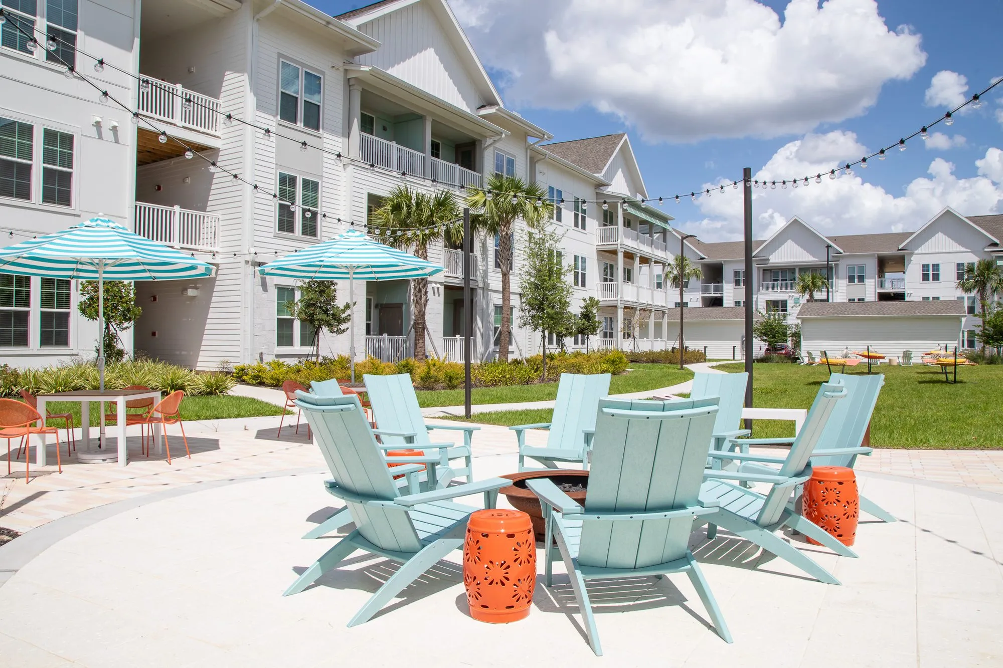 Multifamily amenity courtyard with pale blue Adirondack chairs around a fire pit, interior design by Banko Design at The Brightly, Davenport, Florida