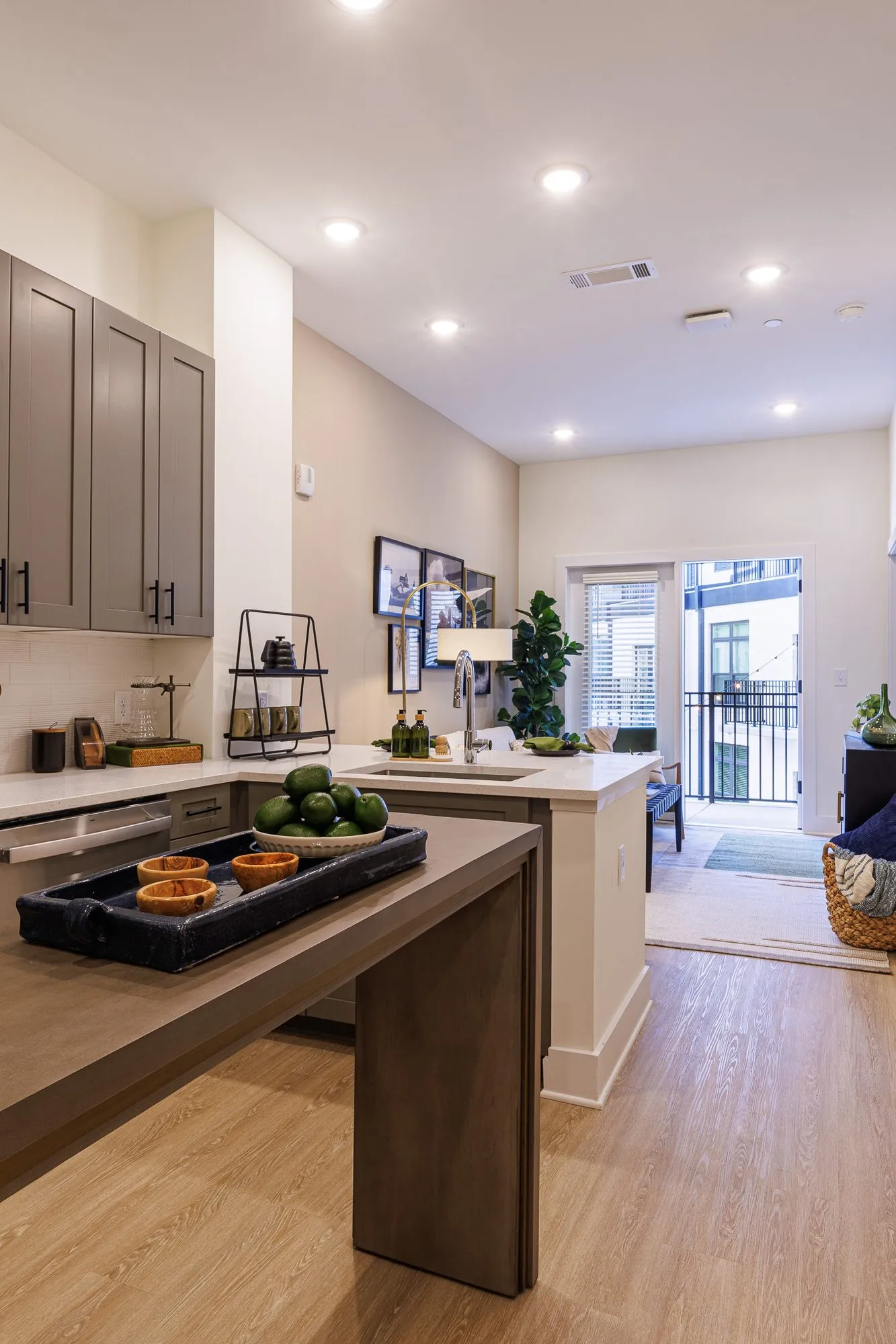 Multifamily model apartment kitchen with grey cabinetry and a peninsula, a wood topped table extension and balcony door