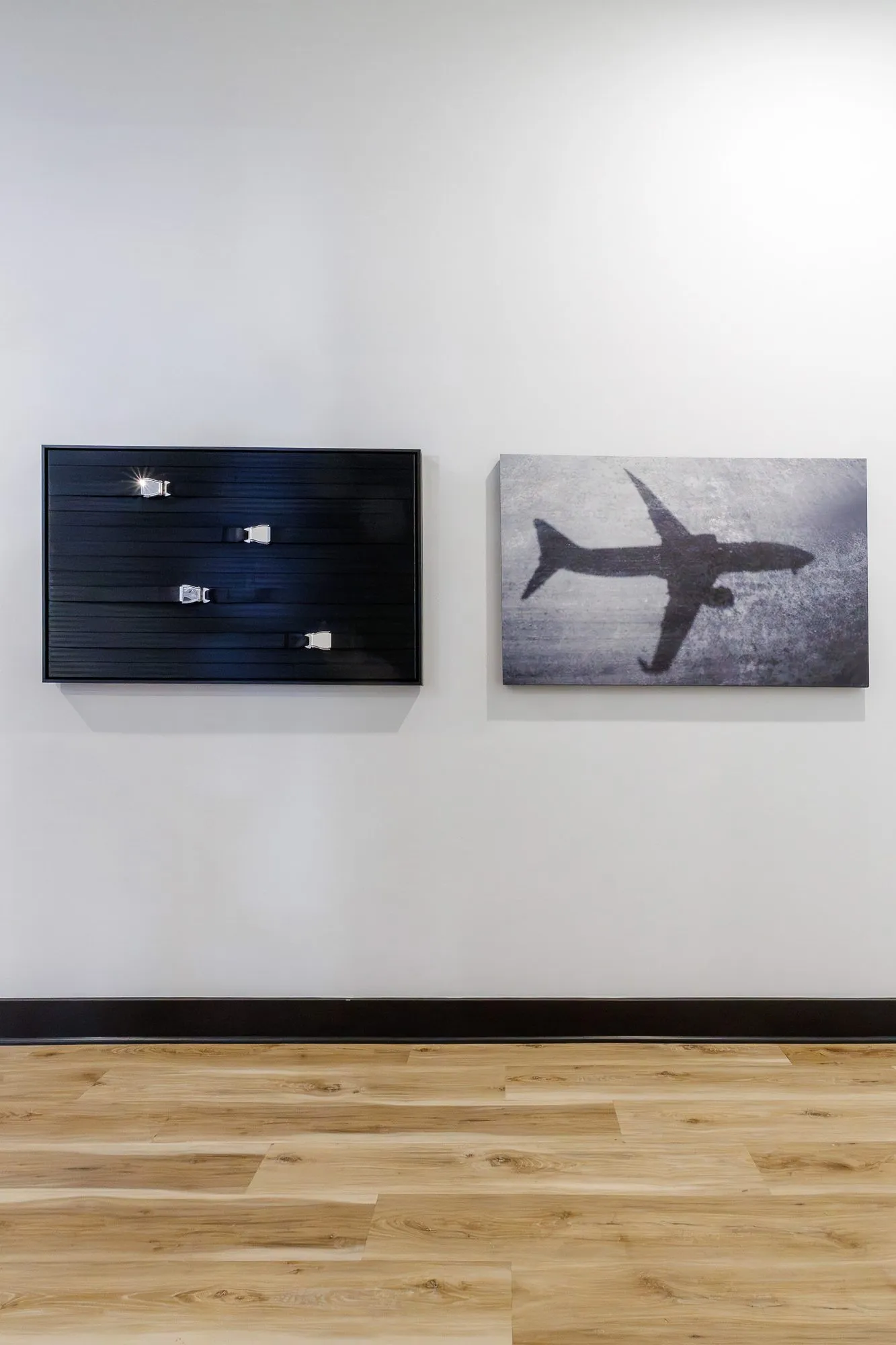 Multifamily interior detail: two framed artworks, a dark panel with small aircraft and a photograph of a plane's shadow
