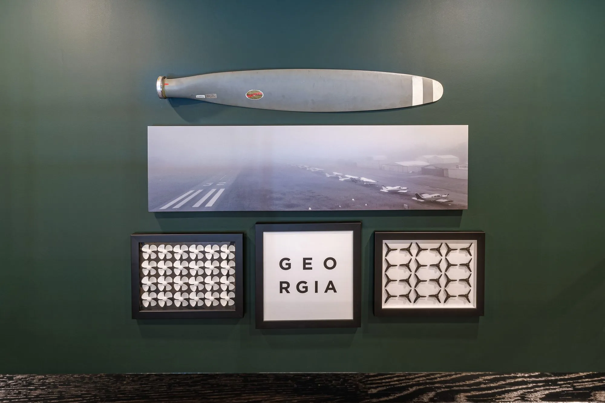 Multifamily interior detail: propeller, runway photograph and three framed prints including a GEORGIA type print on green