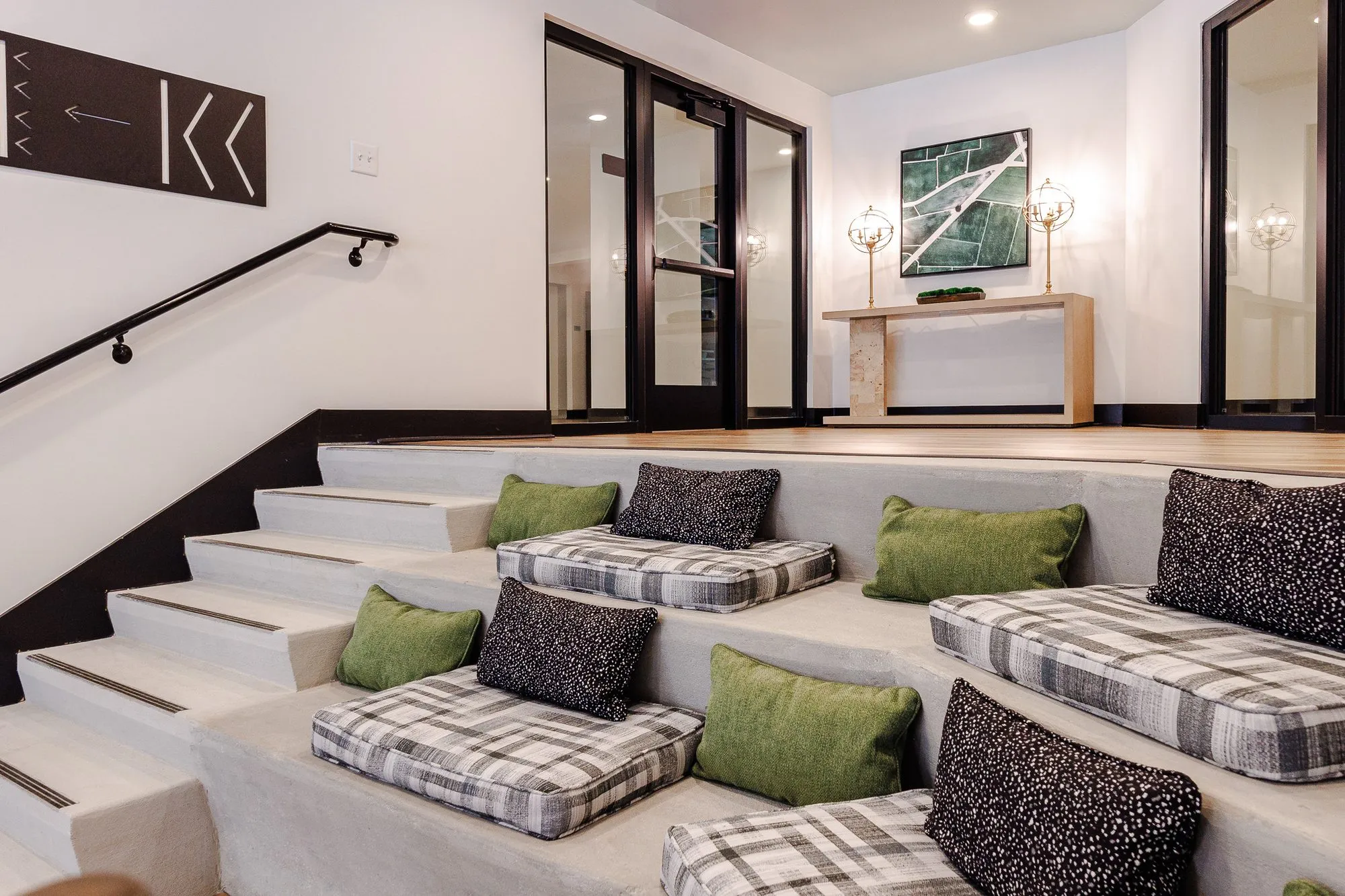 Multifamily amenity bleacher steps with plaid cushions and pillows, a black handrail and arrow wall graphic