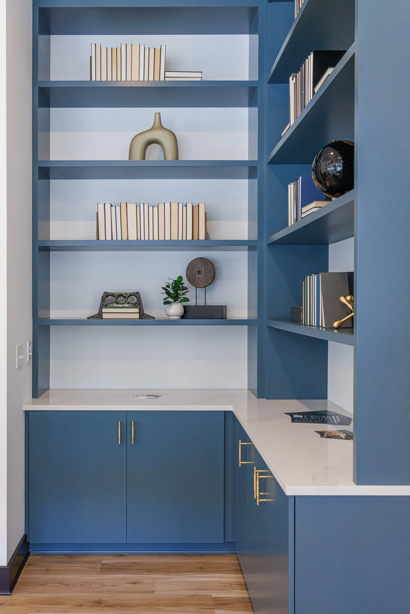Multifamily interior detail: blue built-in shelving and cabinets with brass pulls styled with books and objects