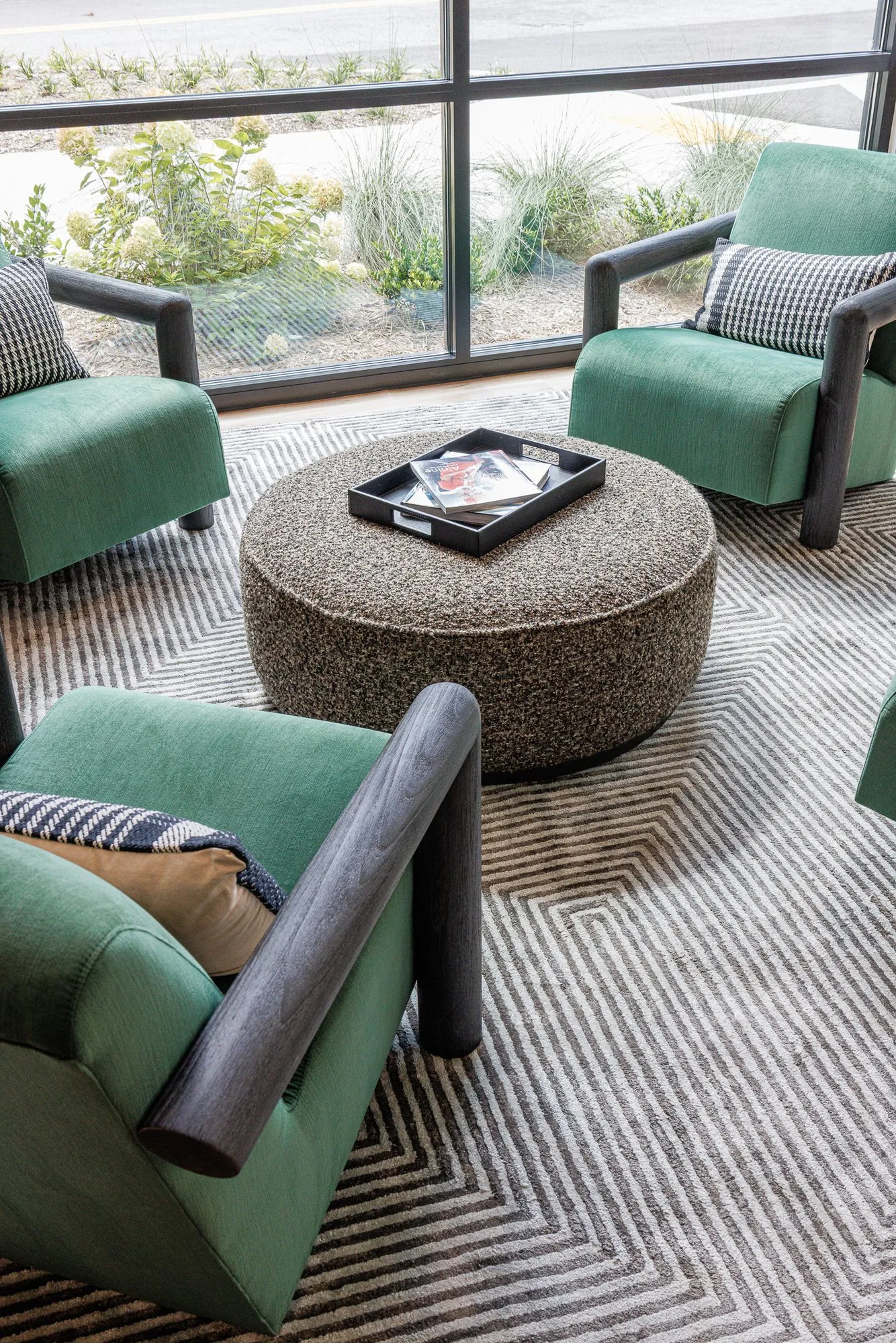 Multifamily interior detail: high angle view of green velvet armchairs with houndstooth pillows around a speckled ottoman