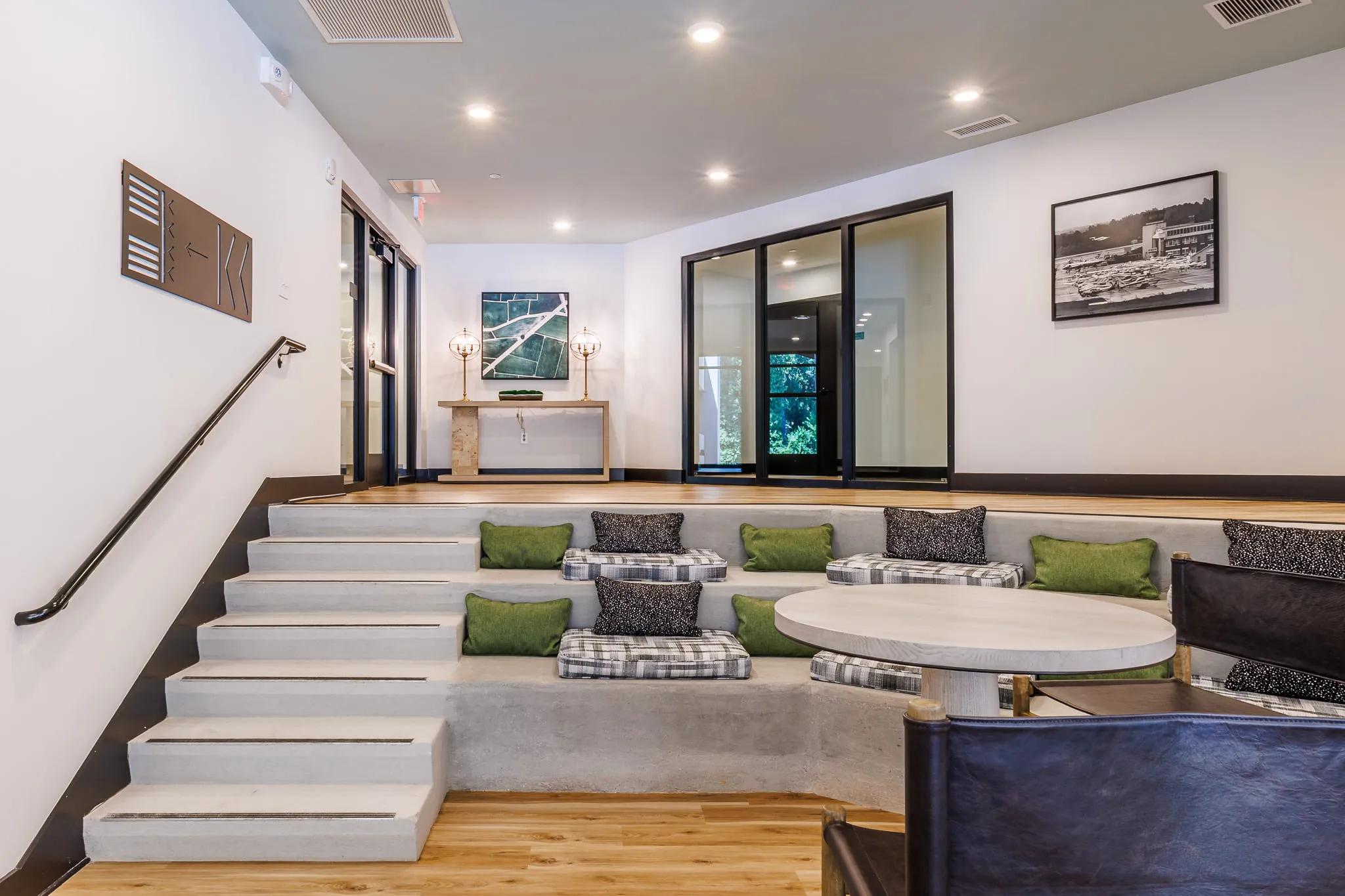 Multifamily amenity tiered bleacher seating with plaid and green cushions stepping down beside the stair rail