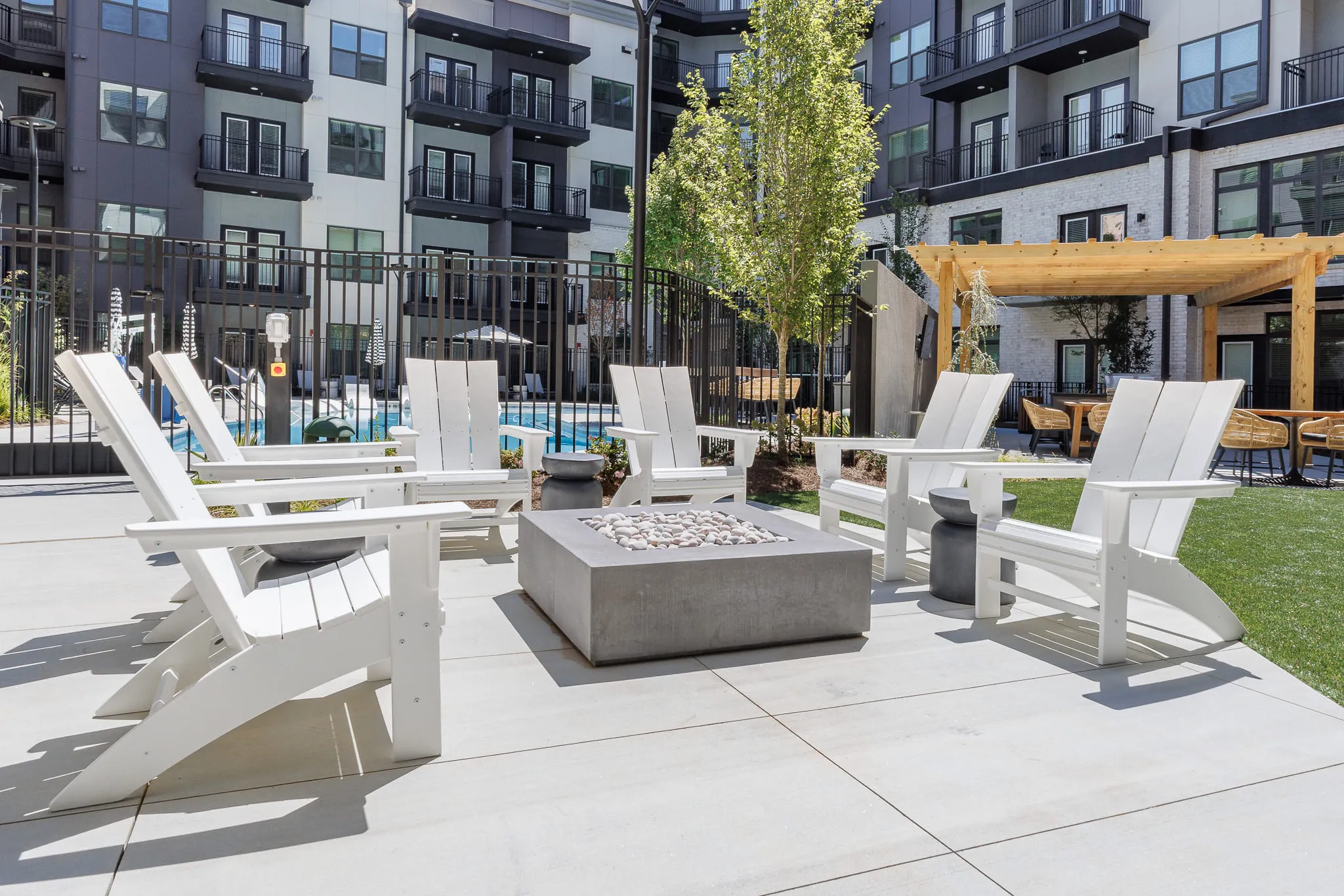 Multifamily amenity courtyard with white Adirondack chairs around a concrete fire table below the residences