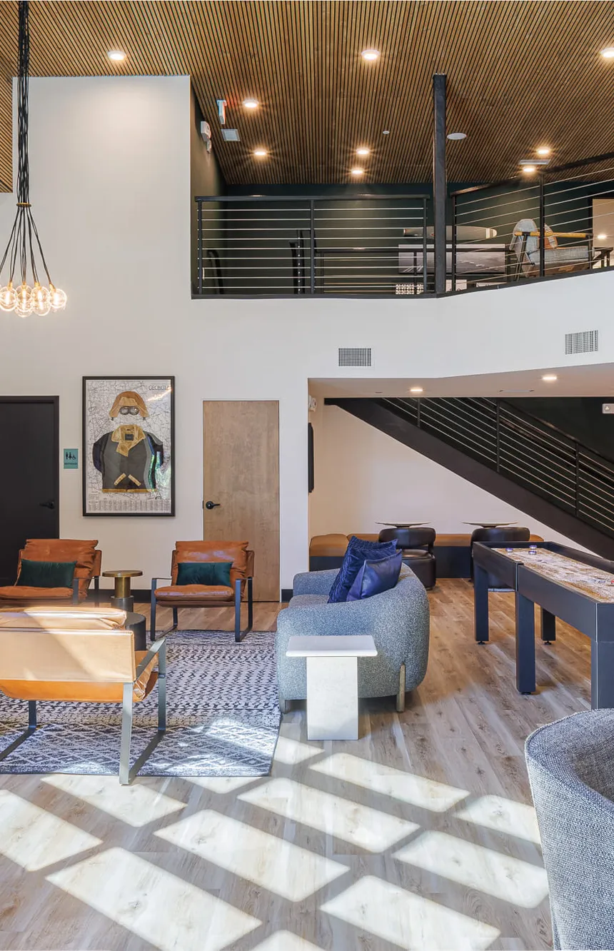 Multifamily double height clubroom with a slatted wood ceiling and a shuffleboard table, interior design by Banko Design at The Hawkins, Chamblee, Georgia