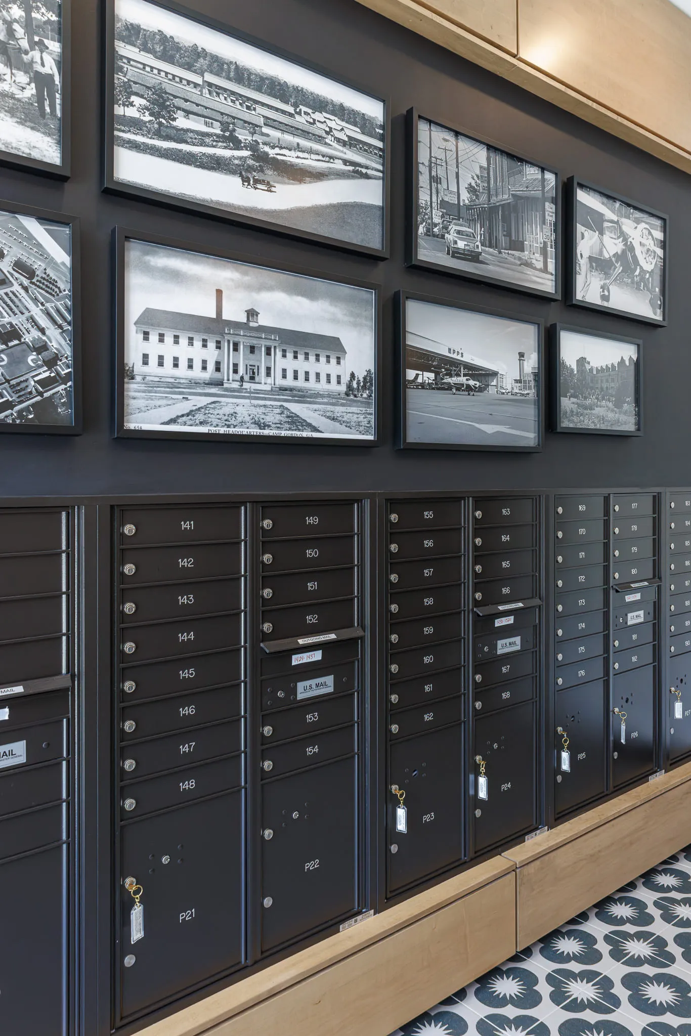Multifamily amenity mail room with black mailboxes below a gallery of historical black and white photographs