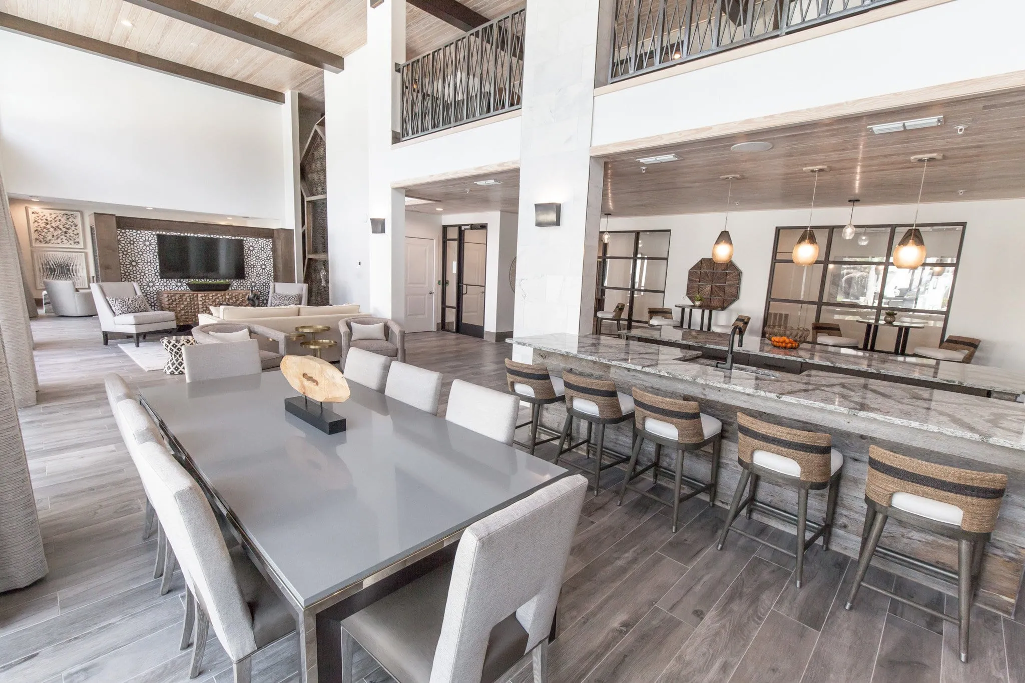 Multifamily amenity clubroom with a communal table beside a marble bar, interior design by Banko Design at The Jaxon, Jacksonville, Florida