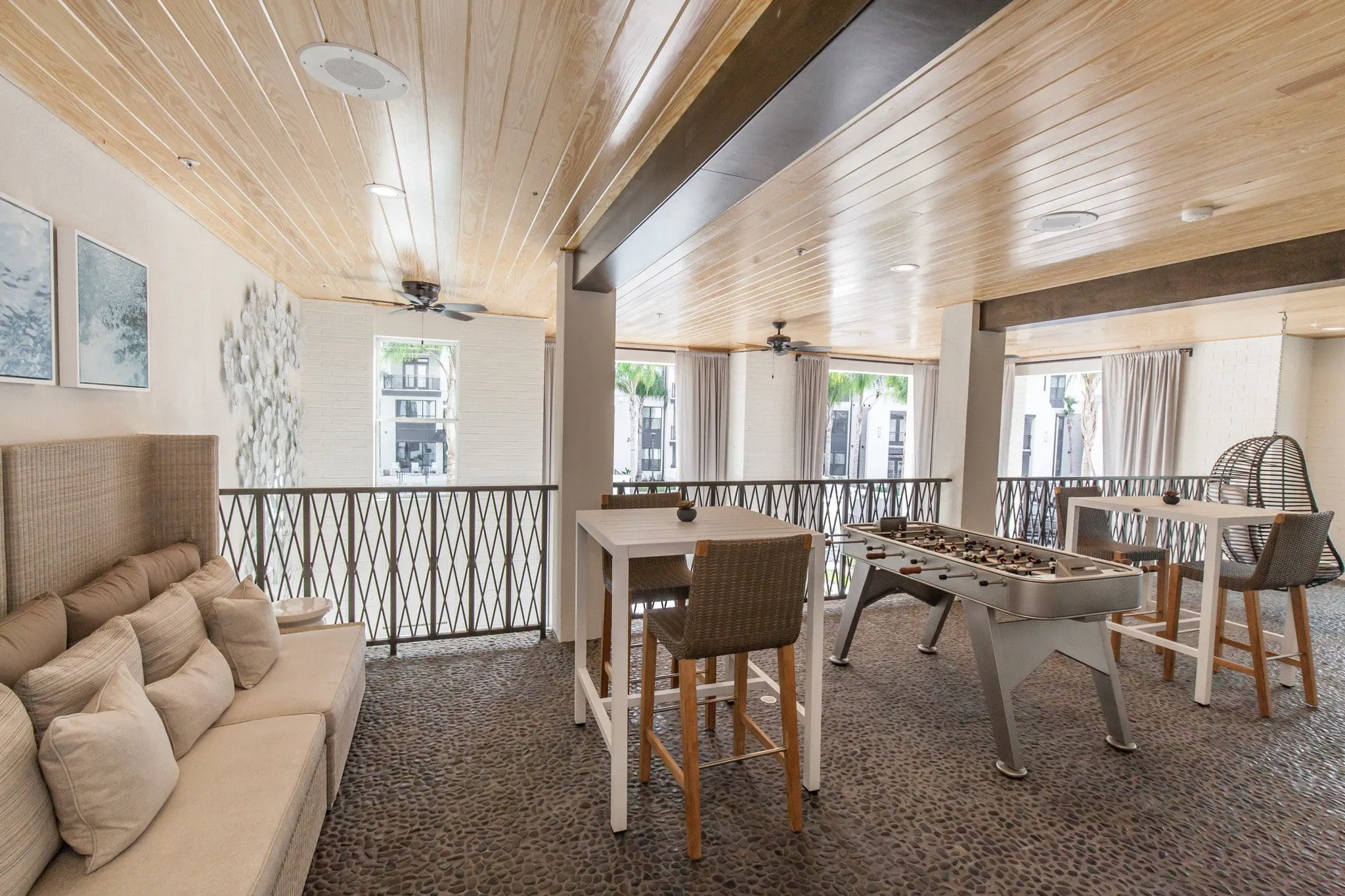 Multifamily amenity game room with a foosball table and lounge seating under a whitewashed plank ceiling