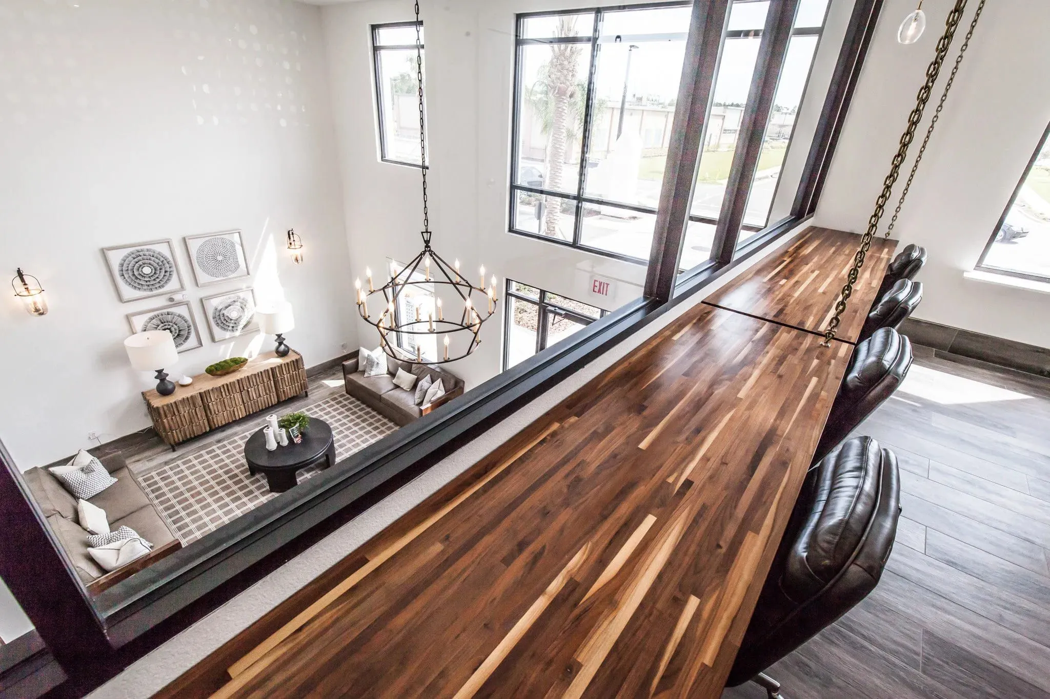 Multifamily amenity mezzanine with a walnut plank counter and black leather chairs overlooking the double-height lounge