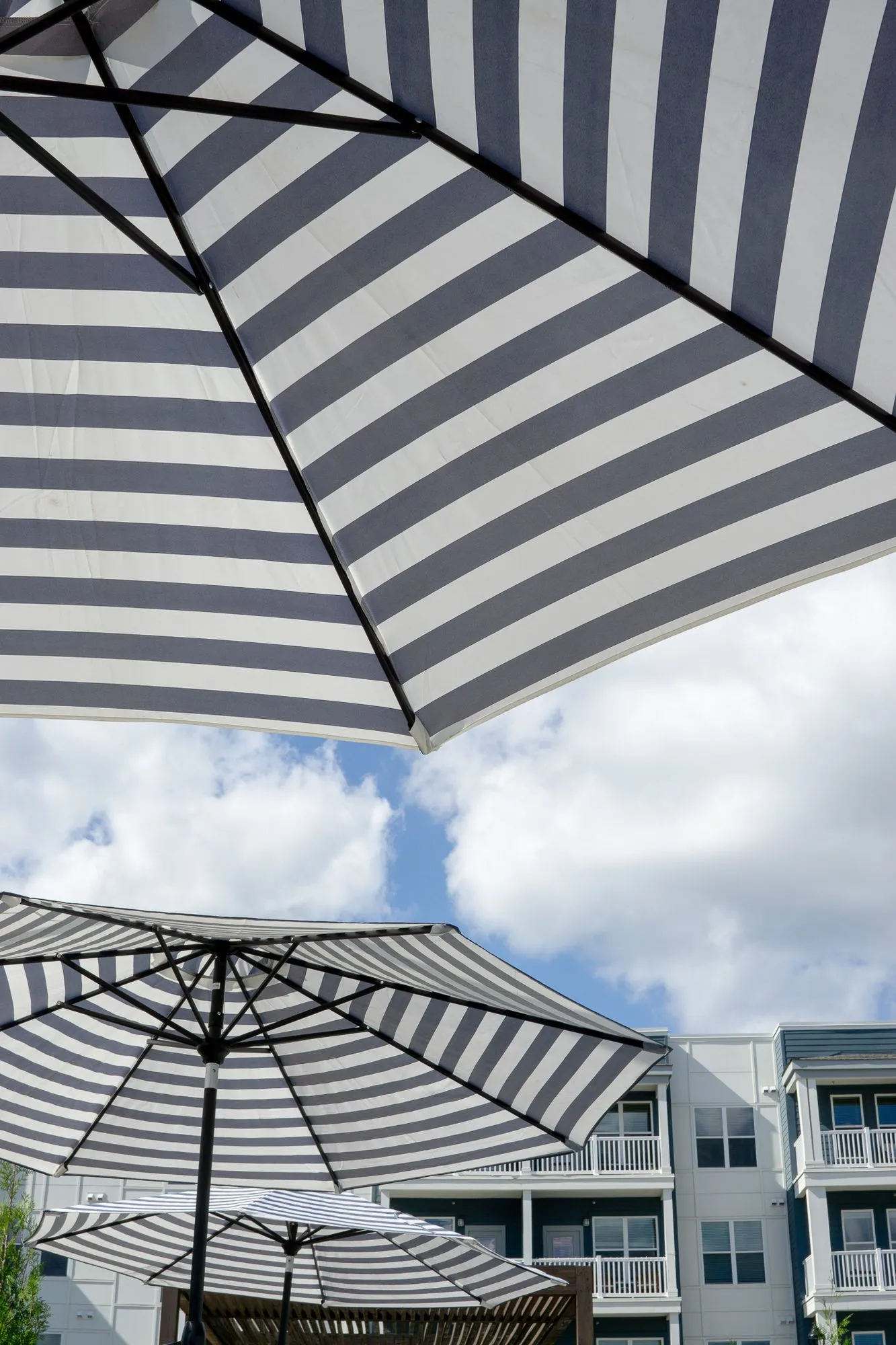 Multifamily community exterior looking up past a navy and white striped umbrella to more umbrellas and balconies