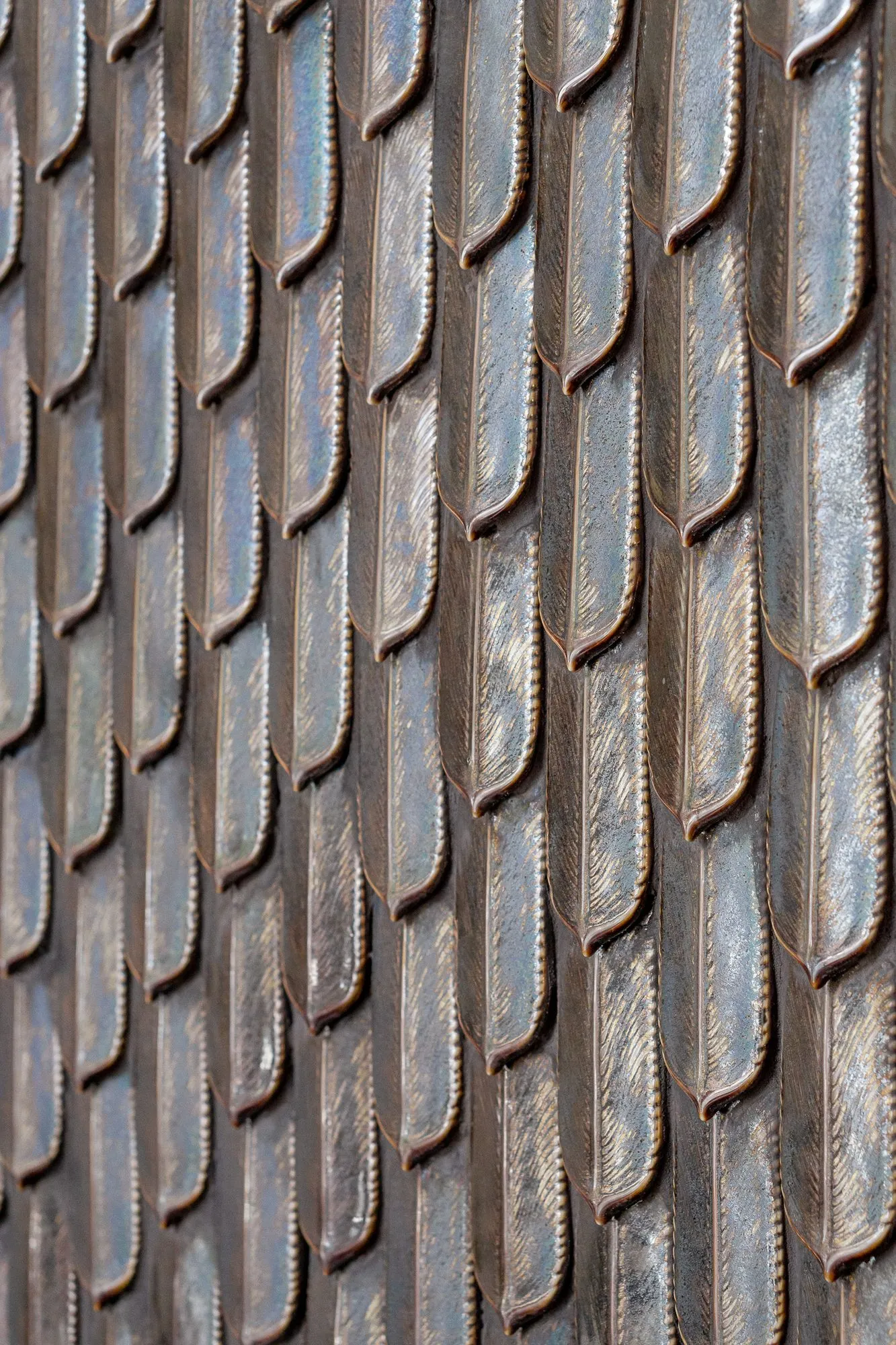 Multifamily amenity lobby wall of iridescent feather-shaped metallic tiles