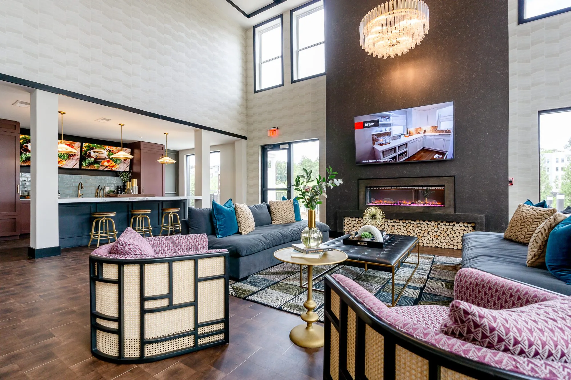 Multifamily amenity fireplace lounge with a cane armchair and navy sofas, the marble bar under pendants at left