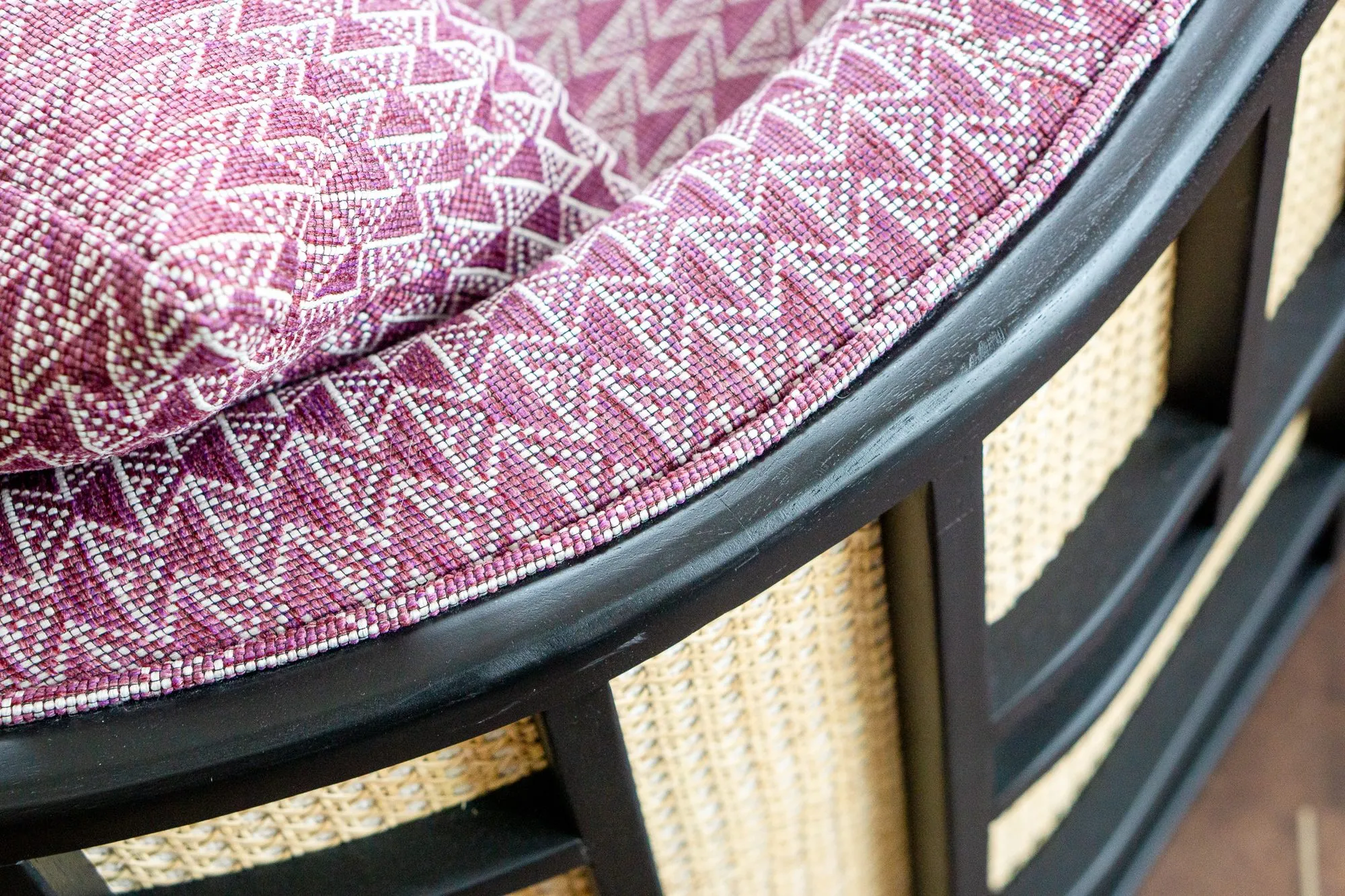 Multifamily amenity interior detail: pink and white zigzag upholstery on a cane and black lacquer armchair