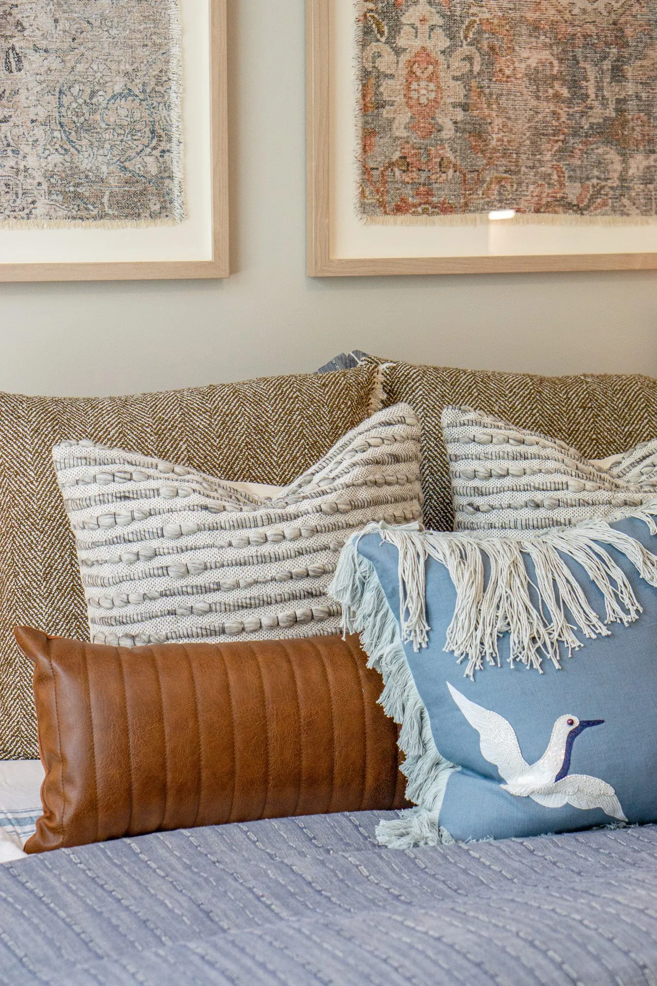 Multifamily apartment bedroom with bird motif bed pillows below two framed textile prints