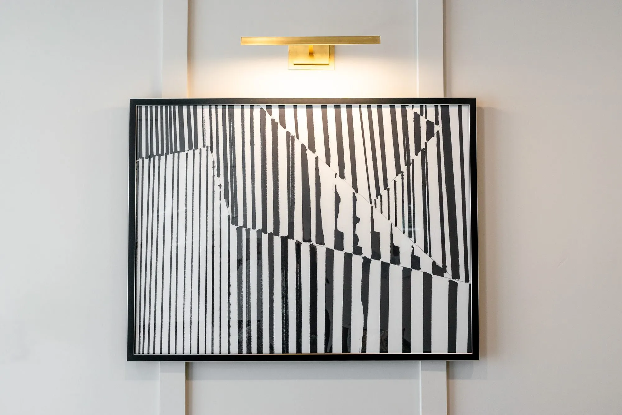 Multifamily amenity leasing area with a framed black and white abstract of broken vertical stripes below a picture light