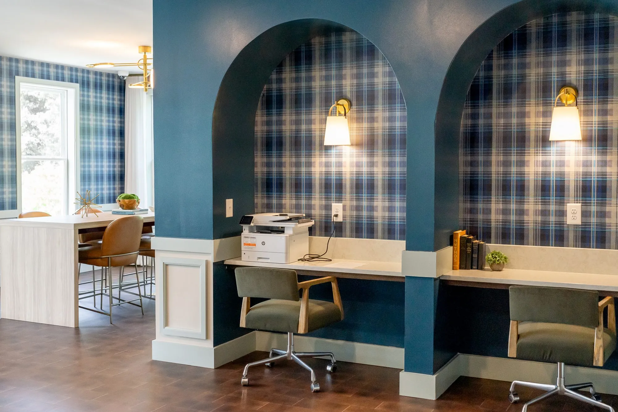 Multifamily amenity arched desk niches with a printer and green chairs, a conference room with a pale wood table beyond