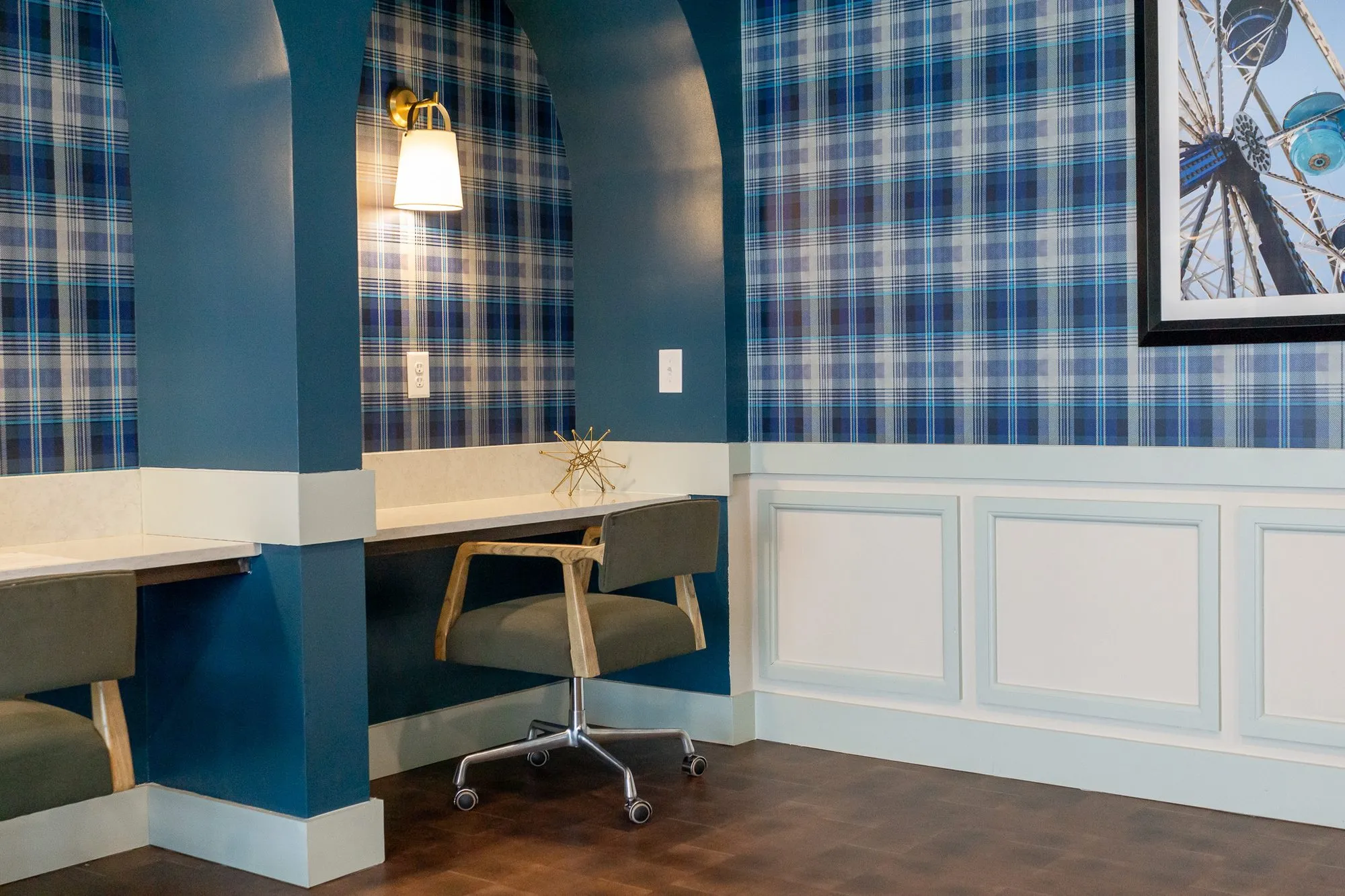 Multifamily amenity arched desk niches with green chairs on castors beside white wainscot and a Ferris wheel print