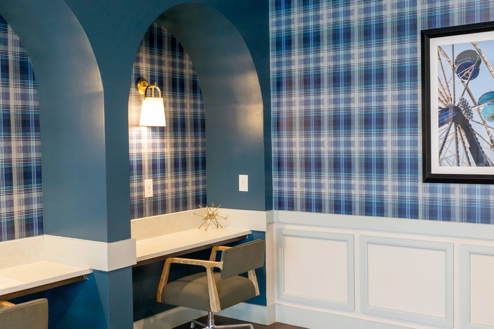 Multifamily amenity arched teal desk niches beside a framed Ferris wheel photograph on plaid wallpaper