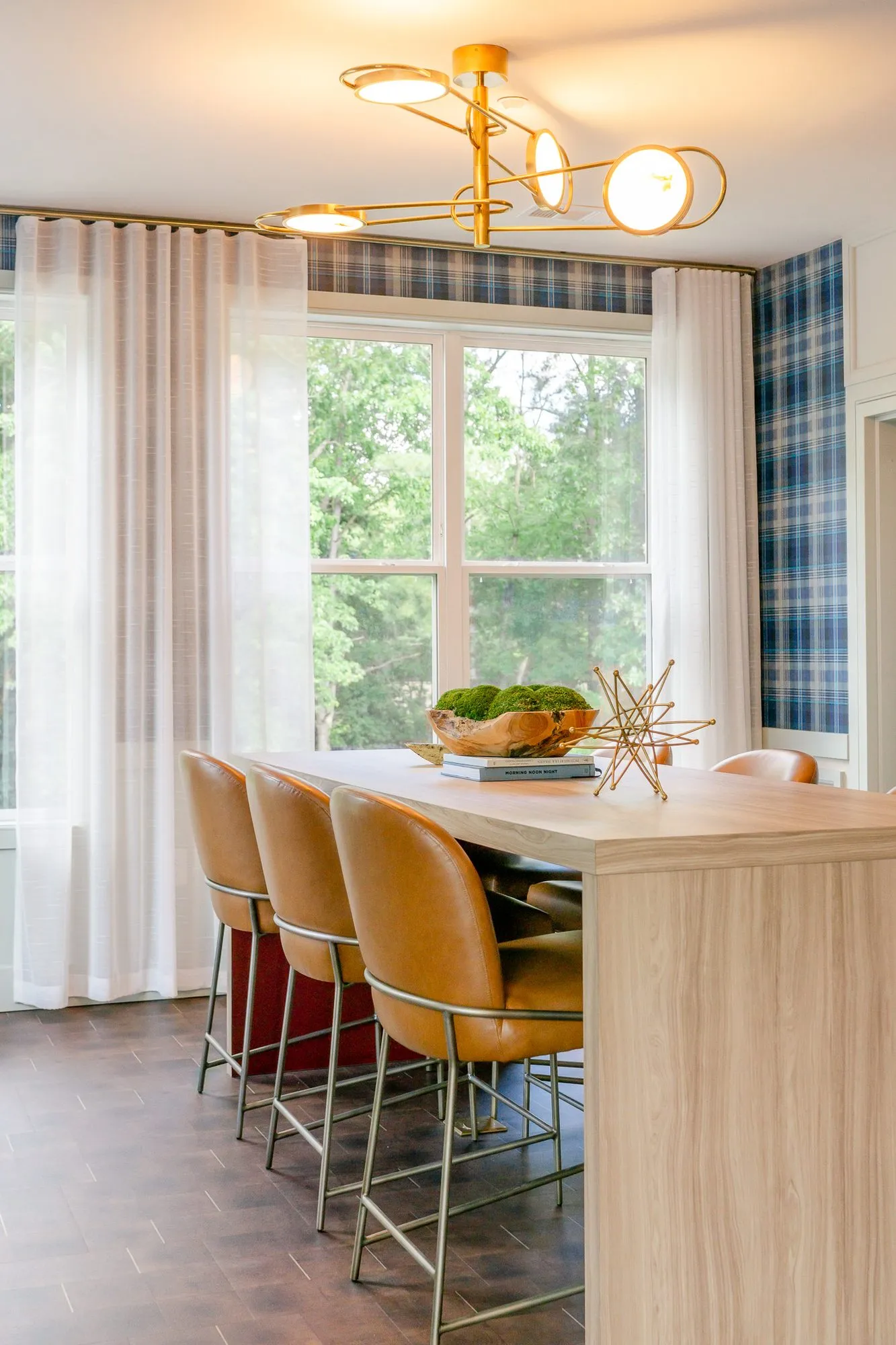 Multifamily amenity conference room with the table and chairs toward sheer-curtained windows under a brass disc fixture