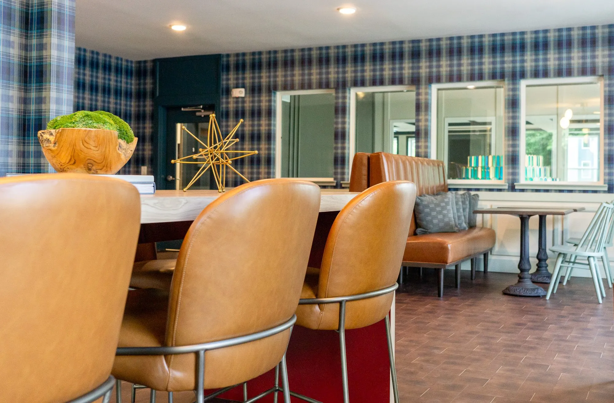 Multifamily amenity conference room, cognac chairs at the table looking toward the cafe banquette and plaid walls