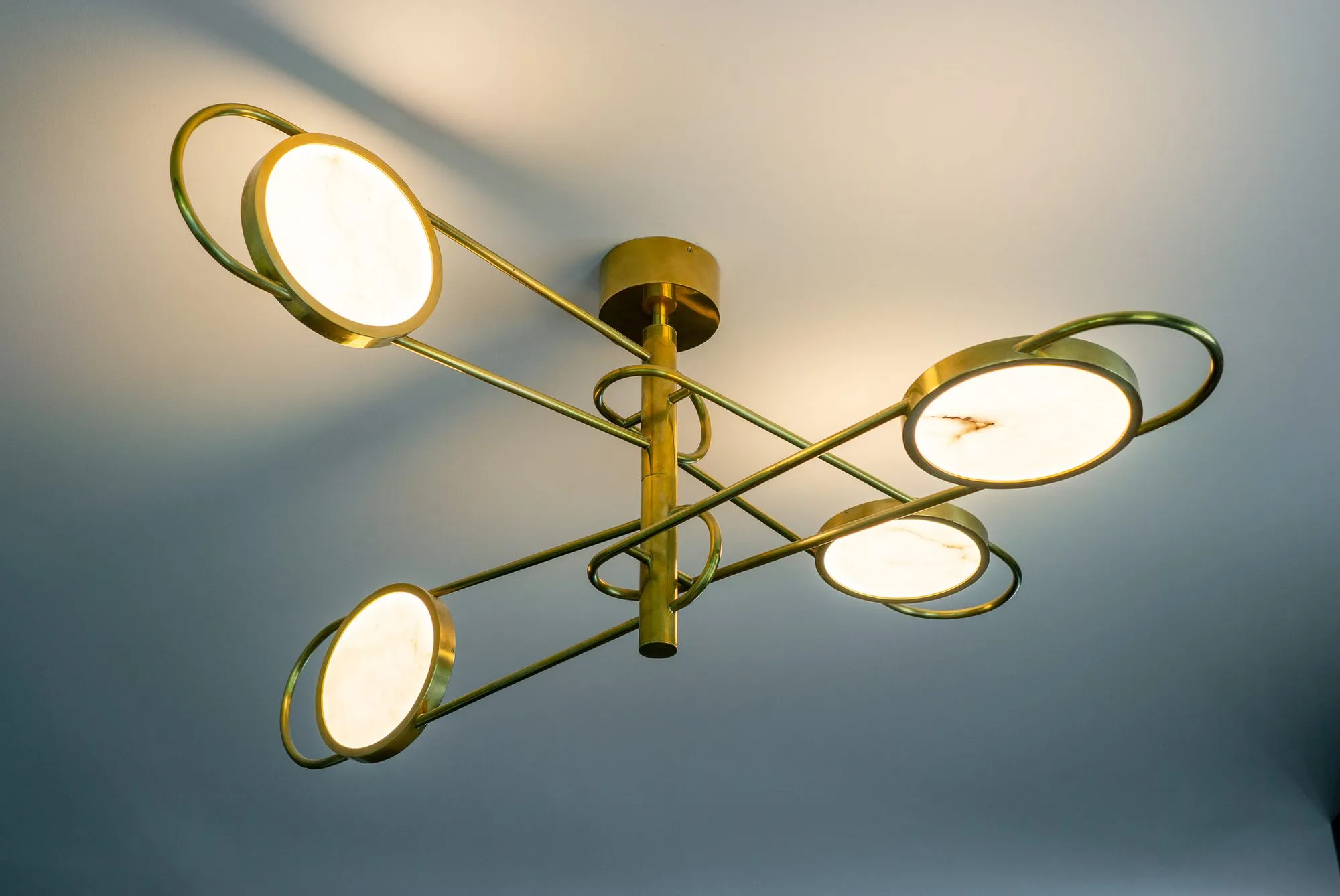 Multifamily interior detail: brass multi-arm ceiling light with its round shades lit