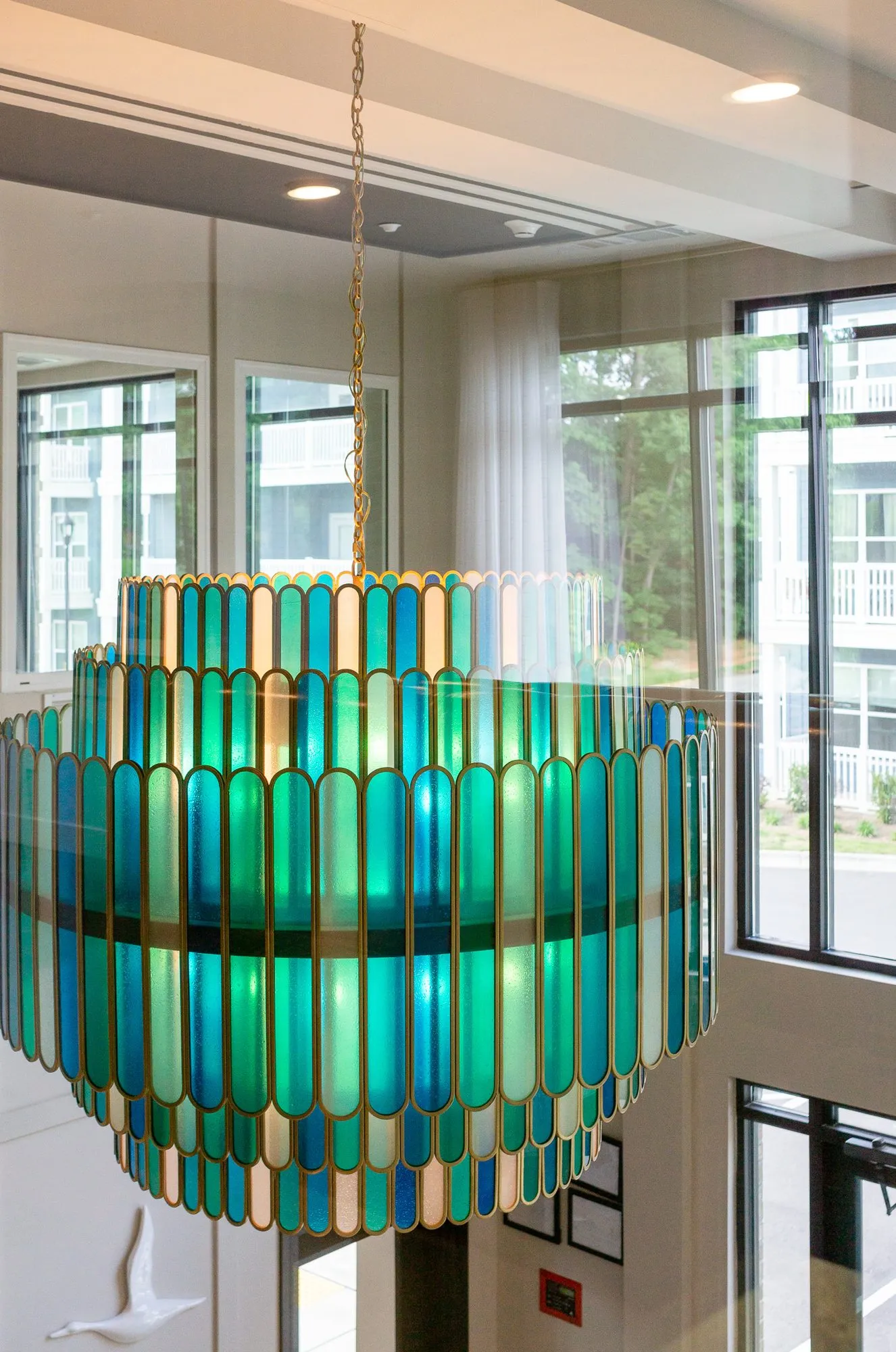 Multifamily amenity lobby with the tiered glass chandelier hanging before tall windows