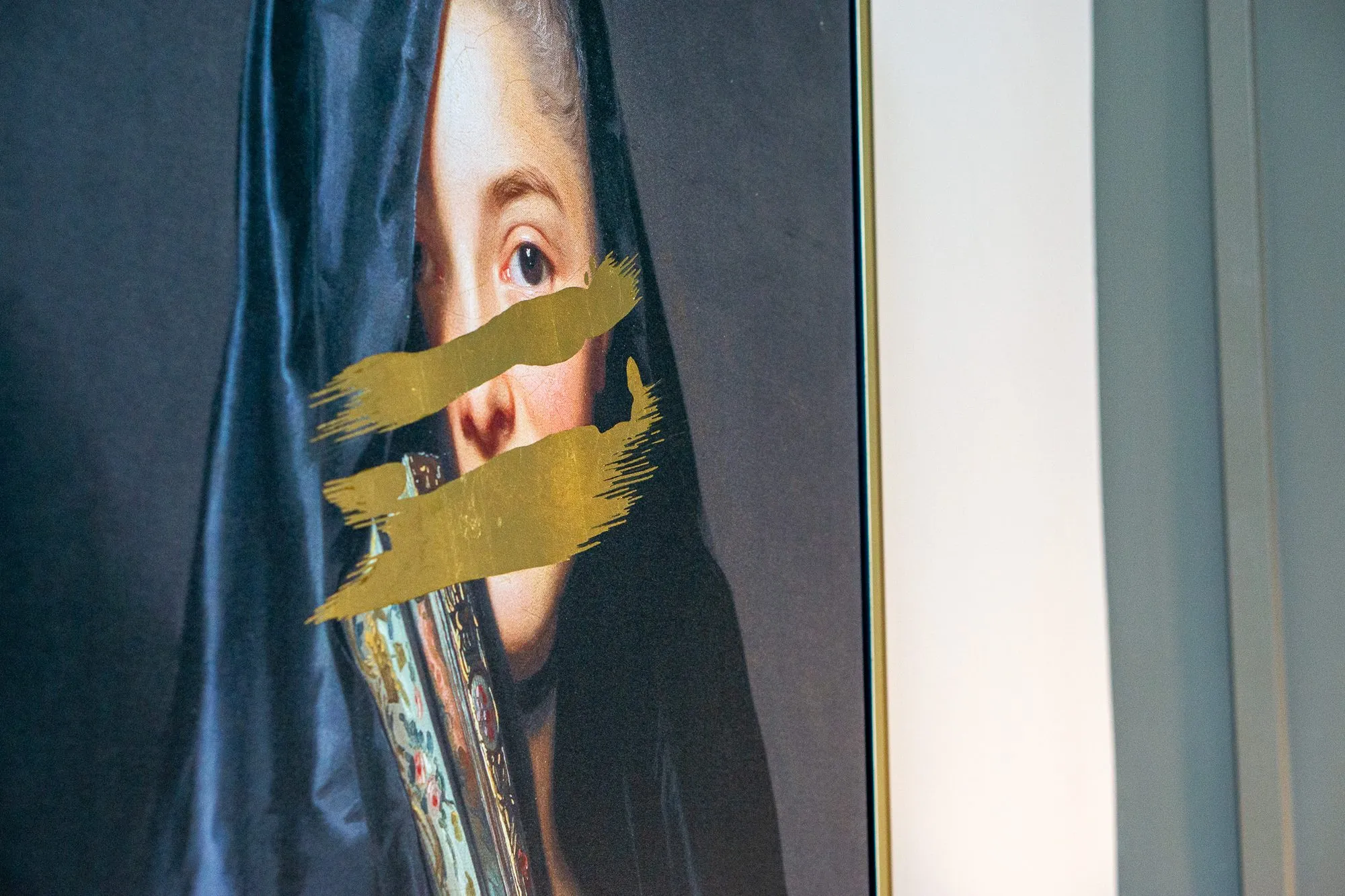 Multifamily amenity lobby lounge artwork, the veiled portrait's face crossed by gold brushstrokes