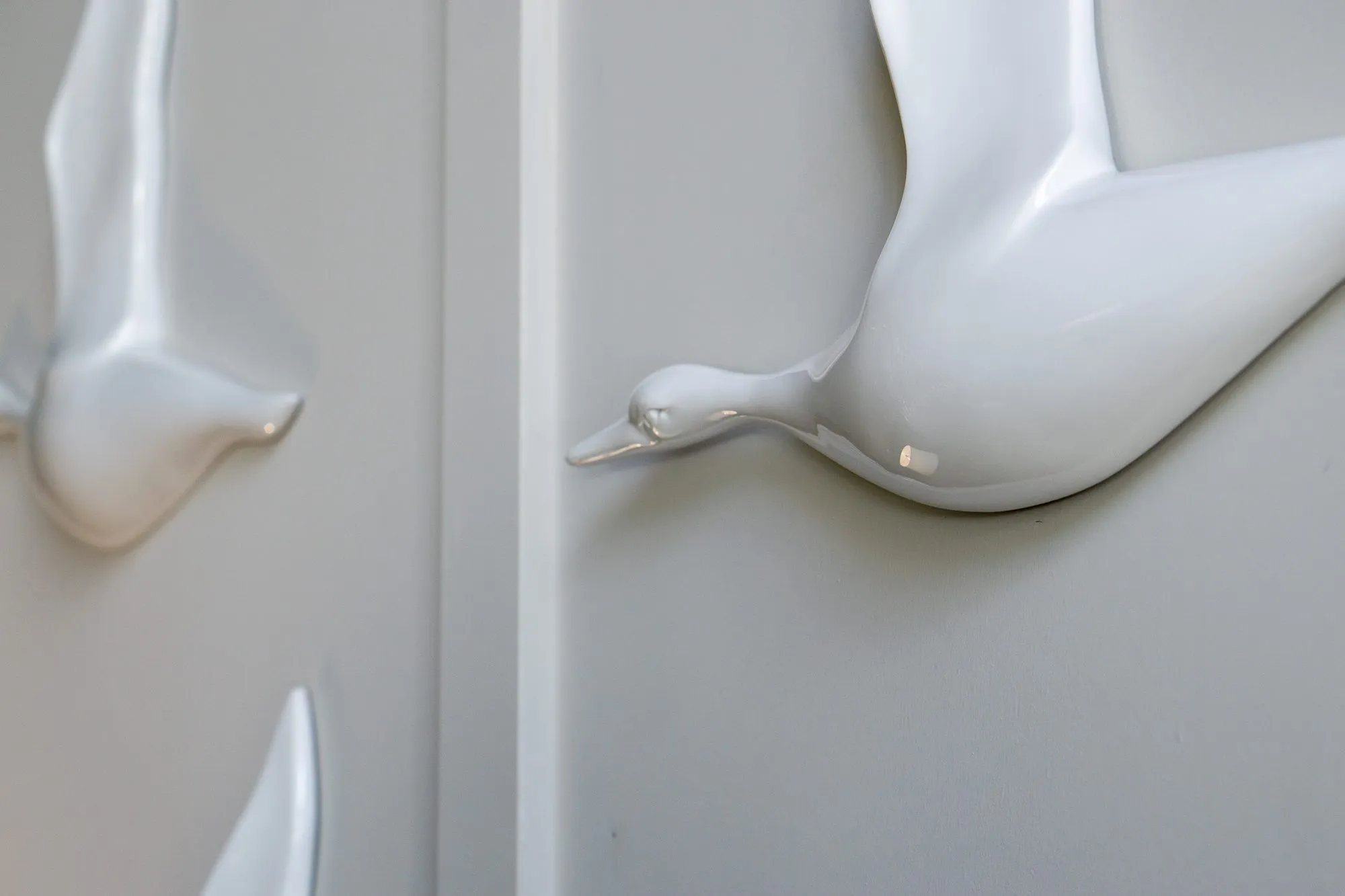 Multifamily amenity lobby wall of glossy white bird sculptures on panelling