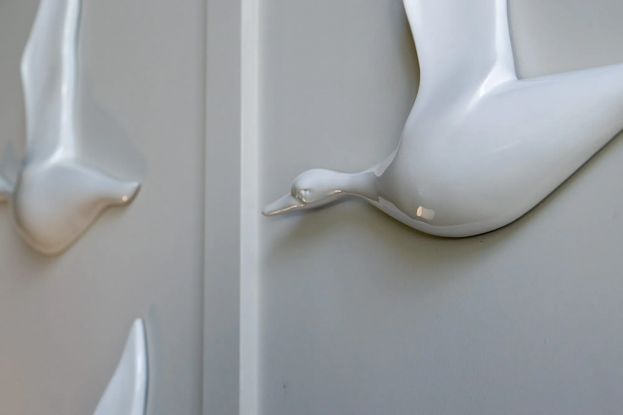 Multifamily amenity lobby wall of white ceramic birds in flight across the panelling, one in sharp focus