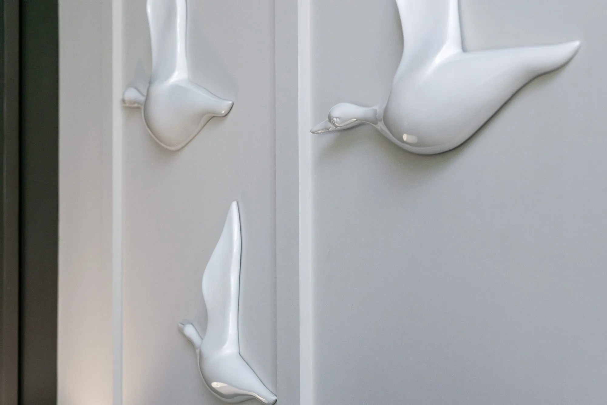 Multifamily amenity lobby wall of three white bird sculptures flying across white panelling