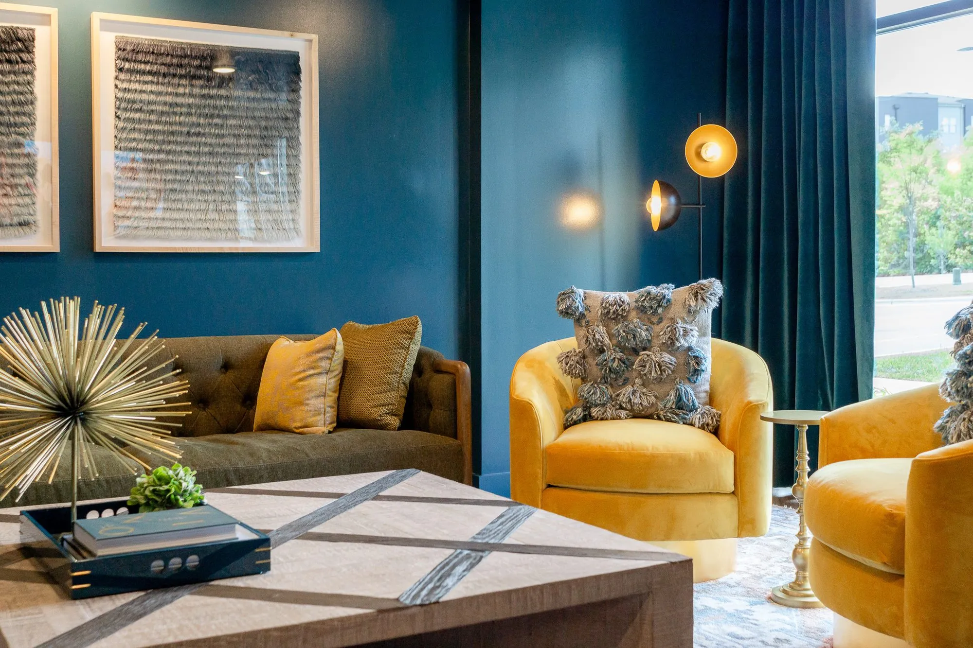 Multifamily interior detail: teal room with yellow velvet swivel chairs and an olive sofa around a block coffee table