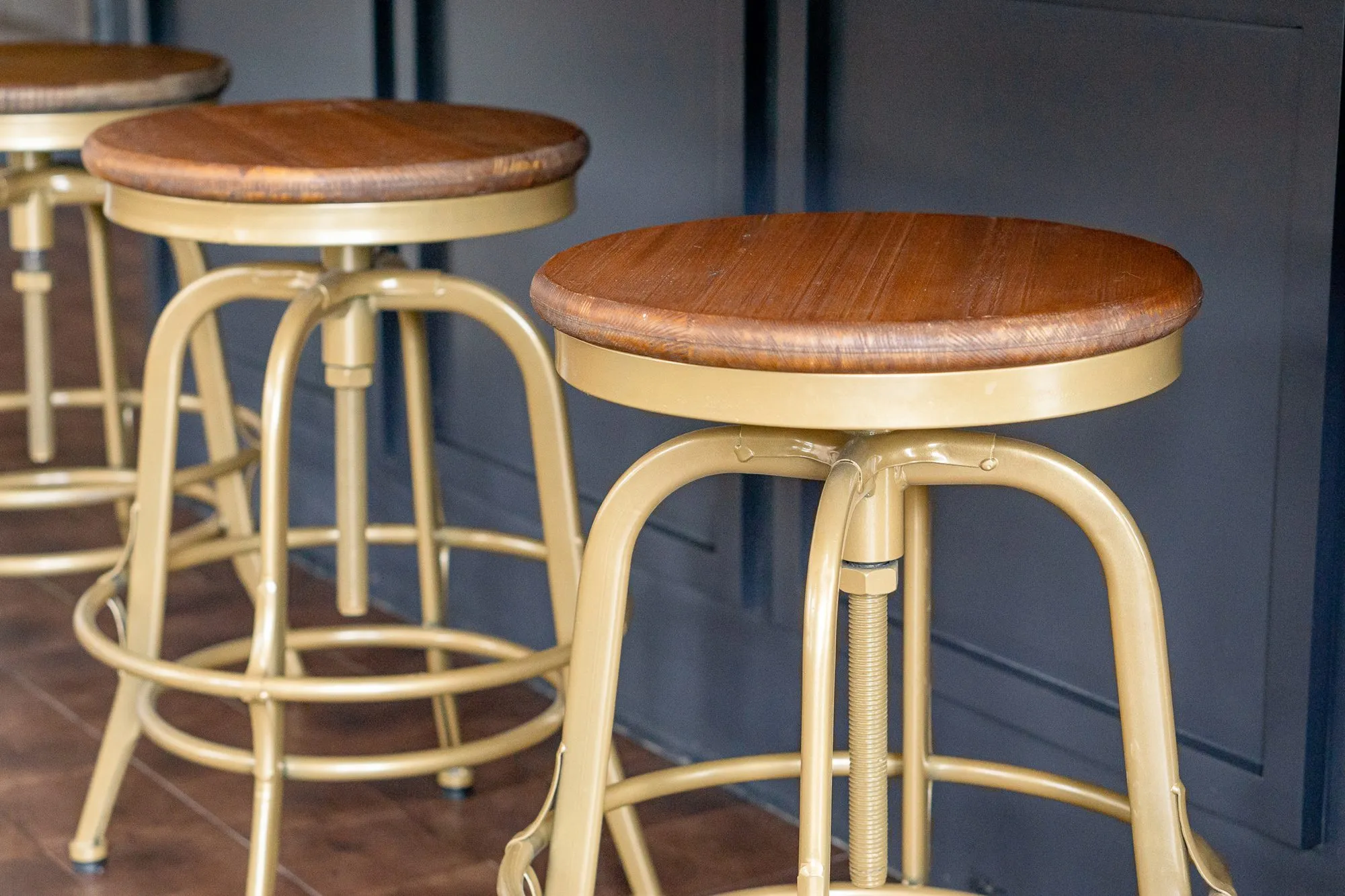 Multifamily amenity bar stools in brass with wood seats against navy panelling