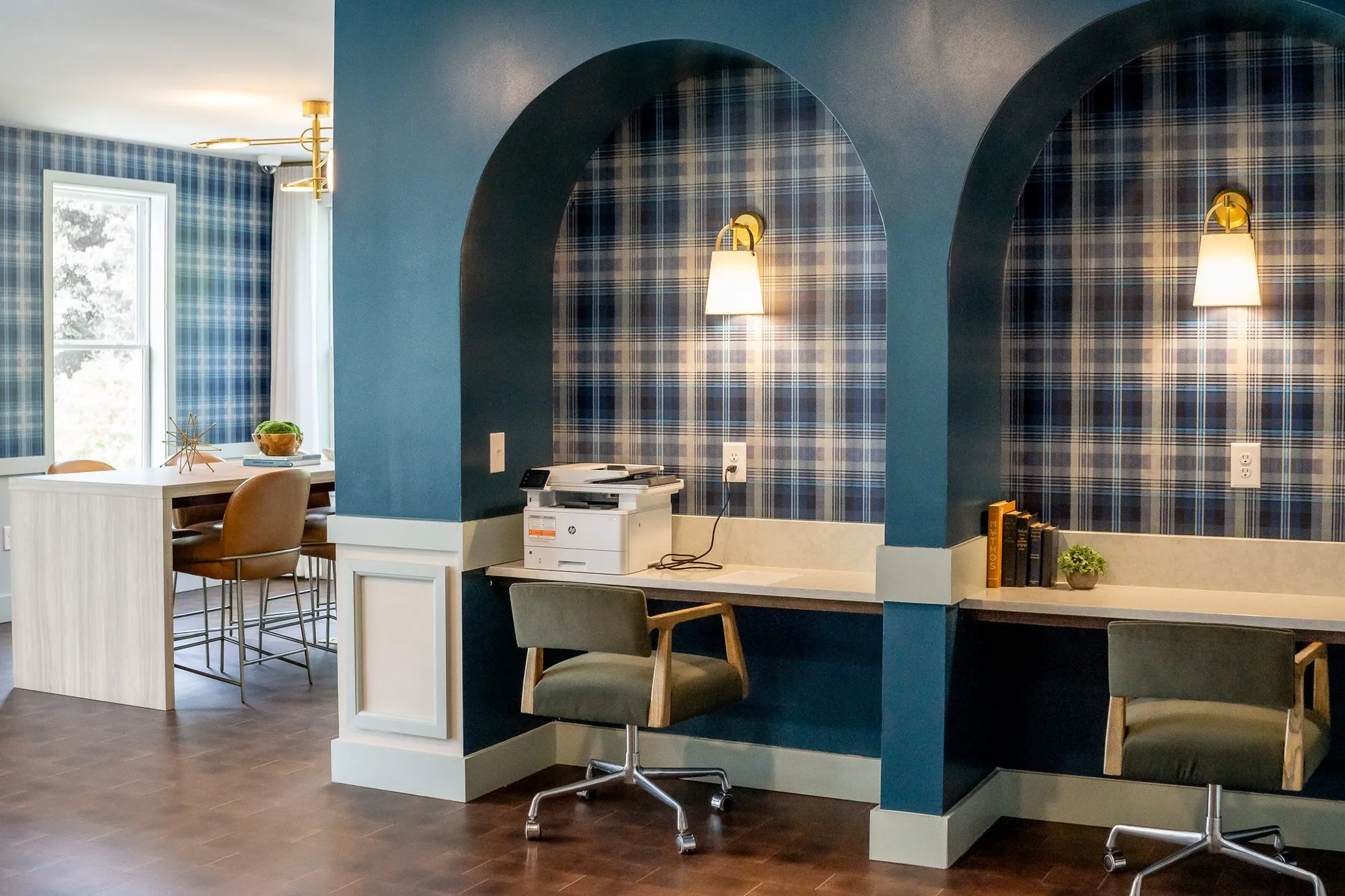 Multifamily amenity plaid-lined desk niches with green chairs and a printer, the conference room beyond