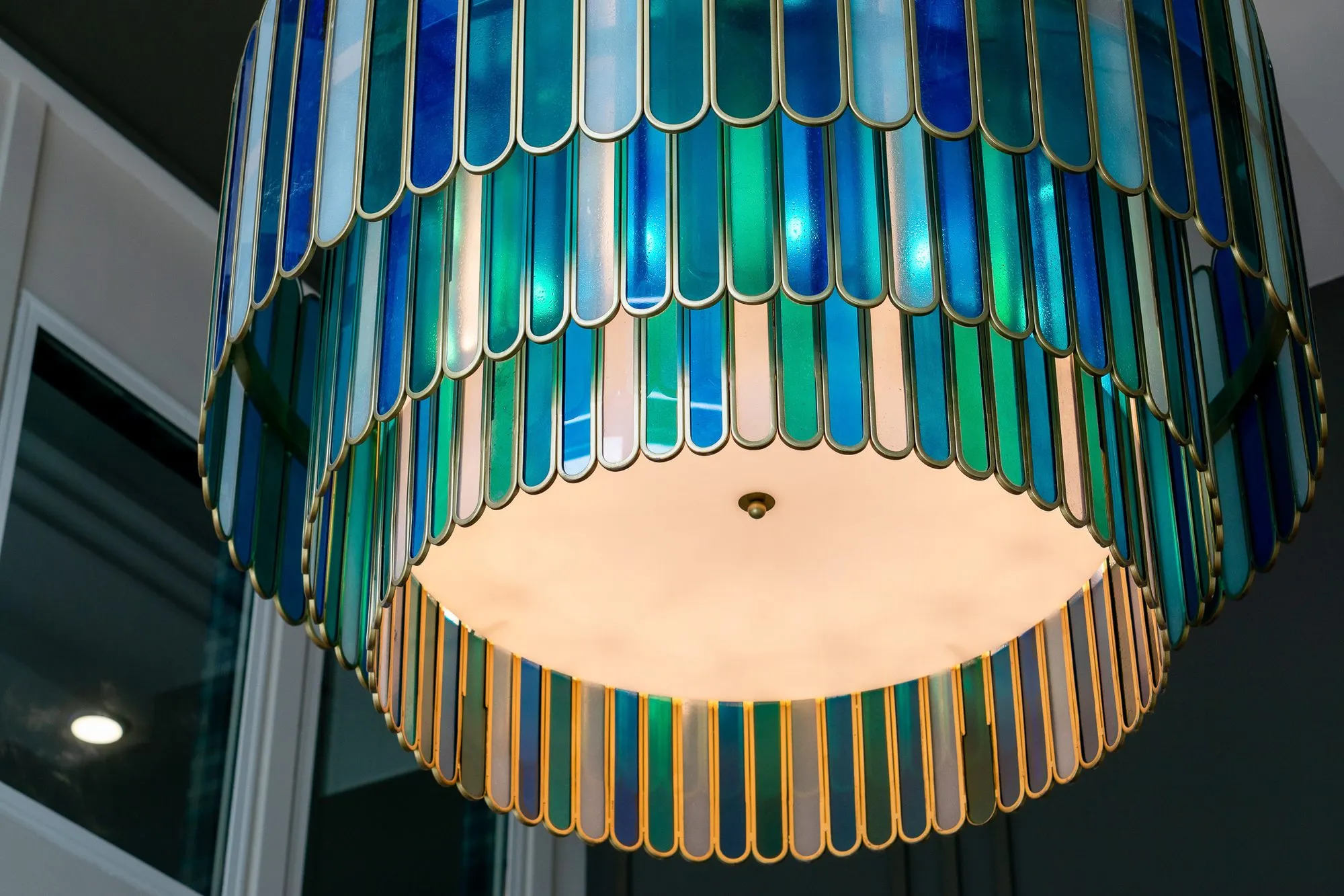 Multifamily amenity lobby chandelier seen from below, tiers of blue and green glass